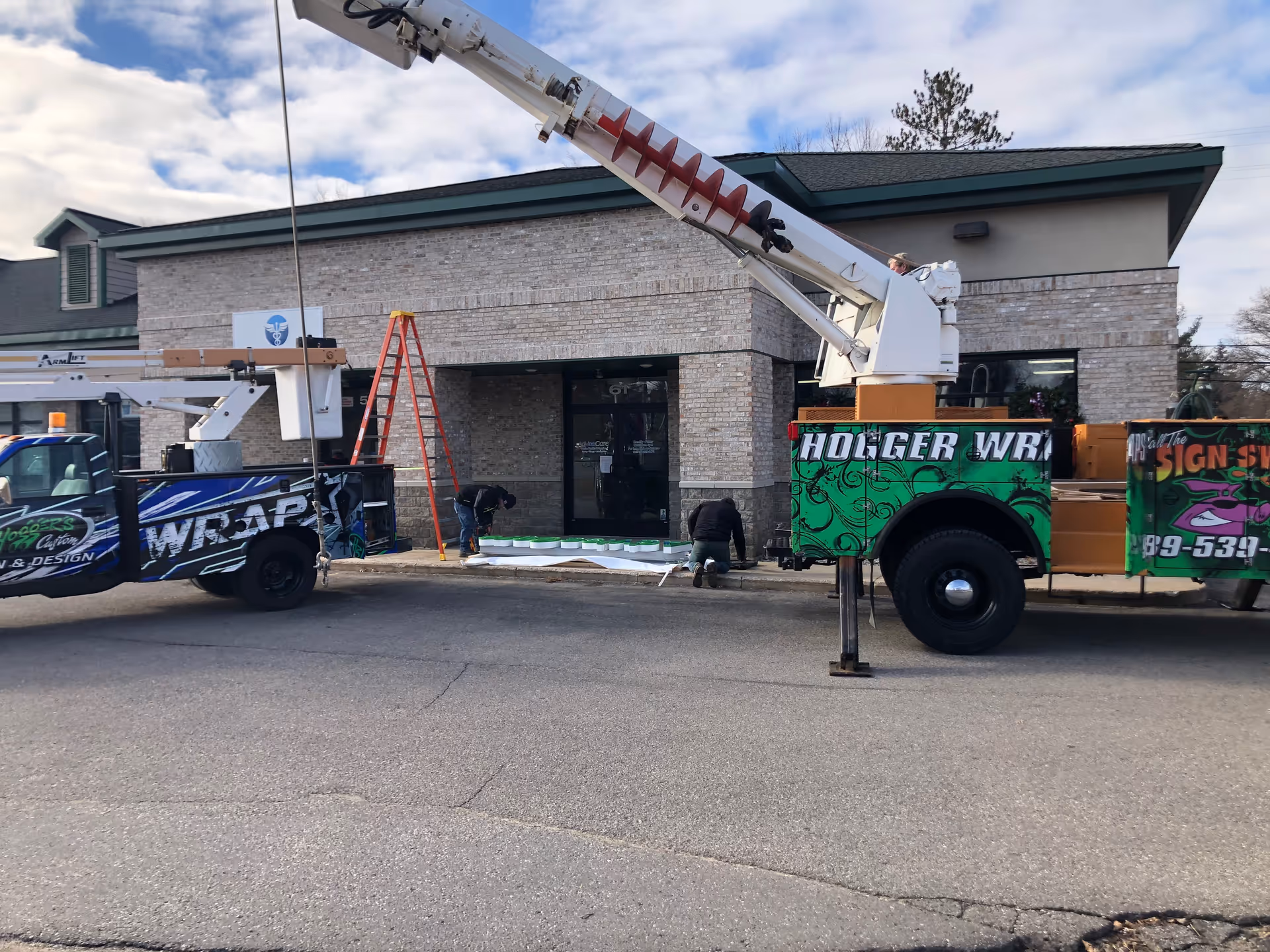 Exterior view of a facility entrance with a large service truck and workers.