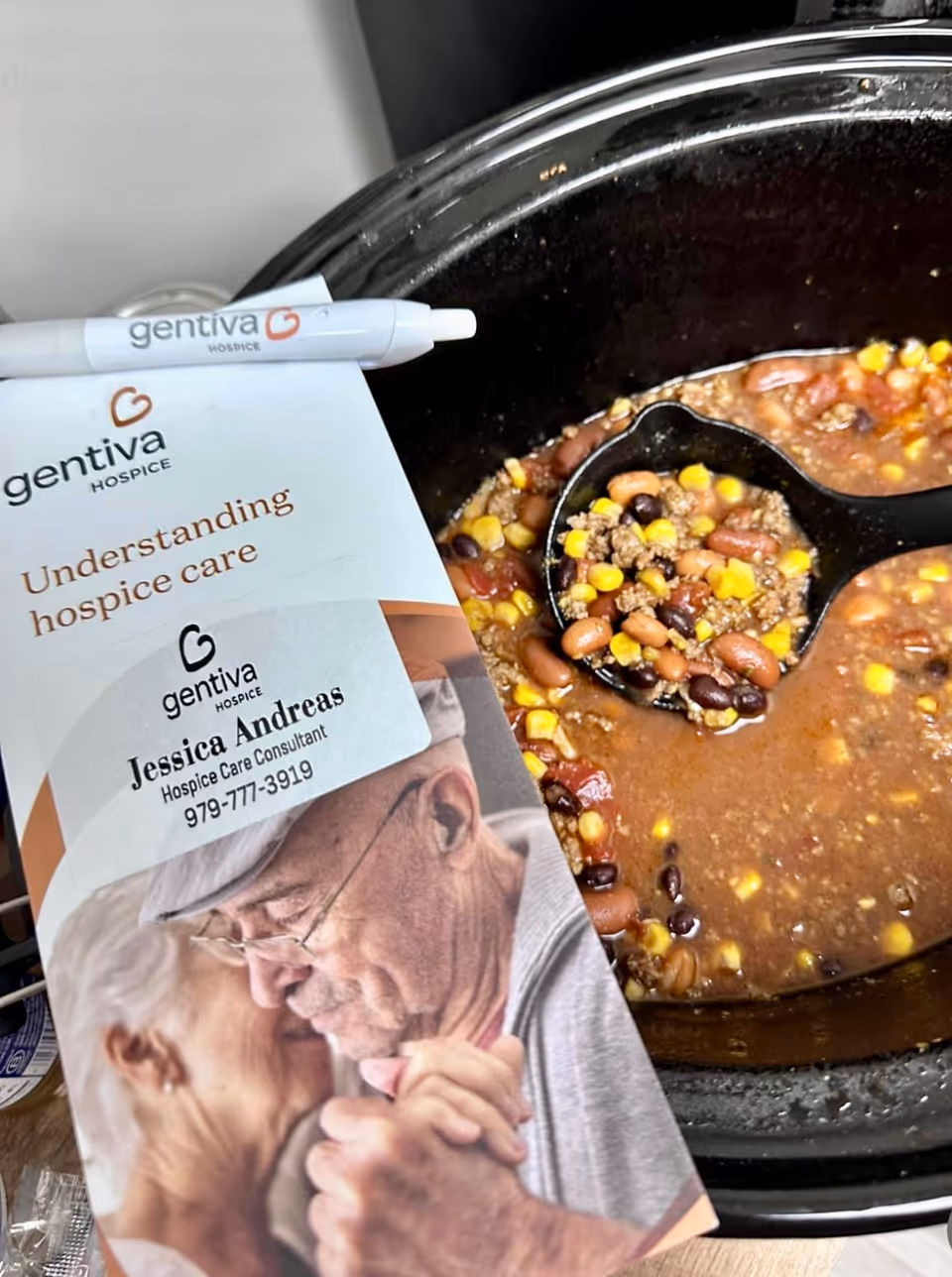 Close-up Gentiva Hospice brochure beside a pot of bean chili soup