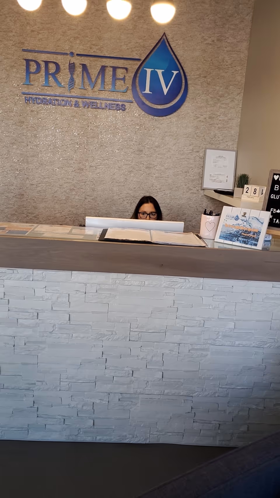 Reception area of Prime IV Hydration & Wellness lobby with receptionist at desk.