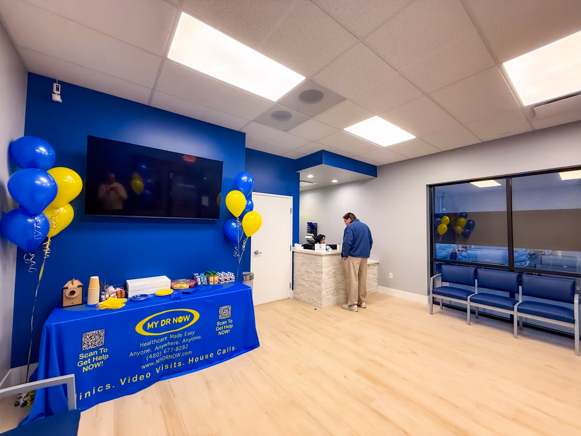 Blue-walled lobby reception area with a desk, balloons, TV, and seating.
