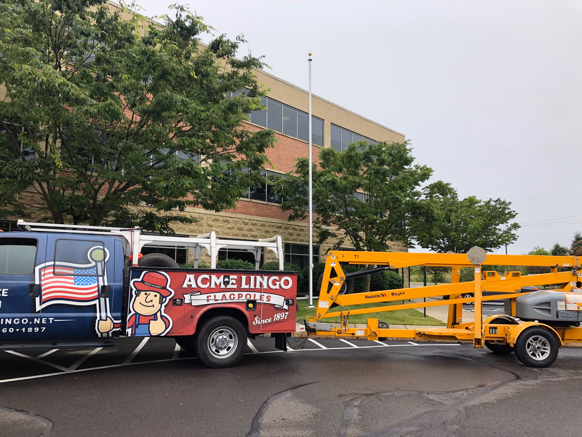 Exterior view of a brick facility with trees and a service truck in the parking lot.