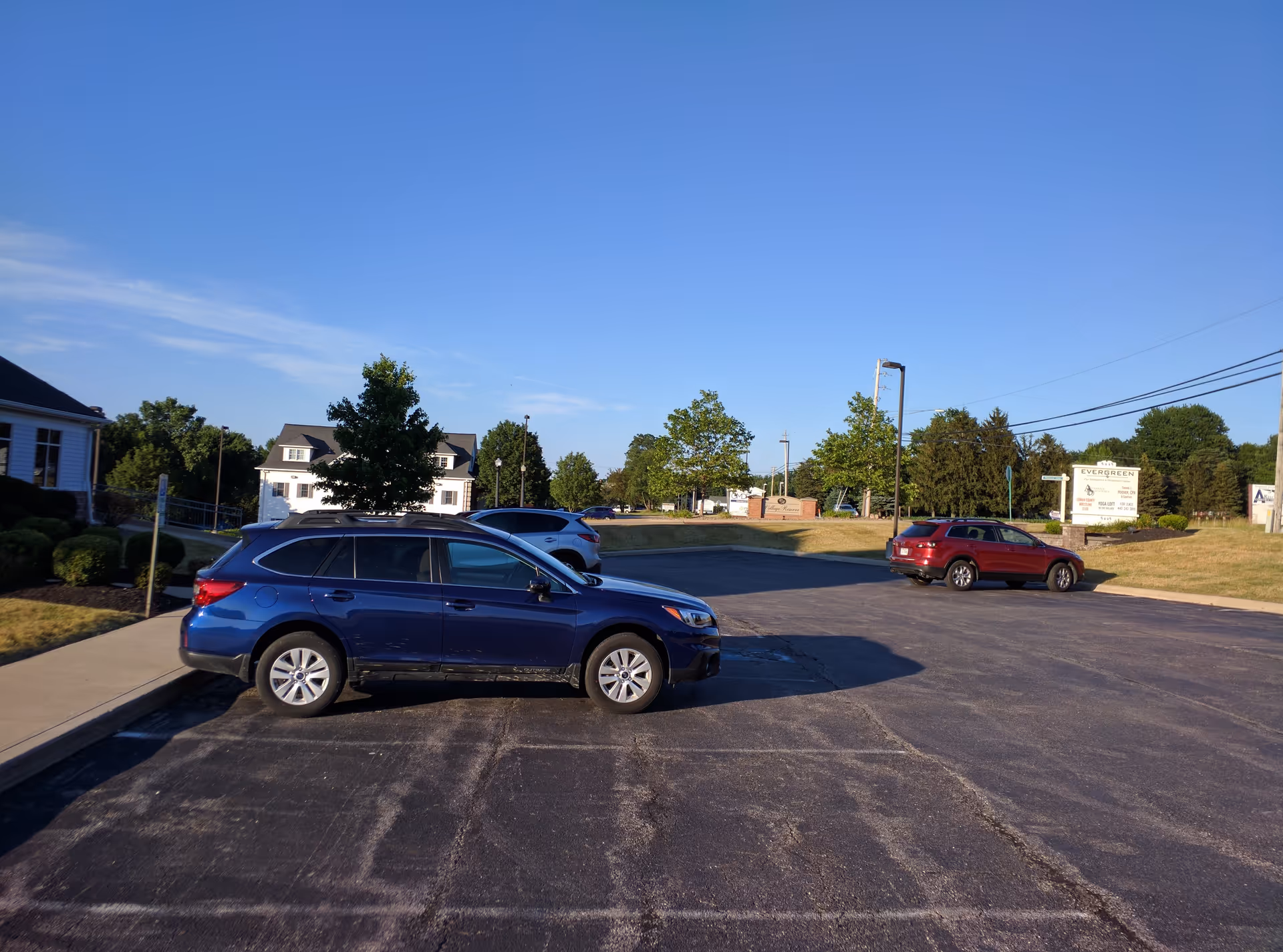 Parking lot with several cars in front of Evergreen facility under a blue sky