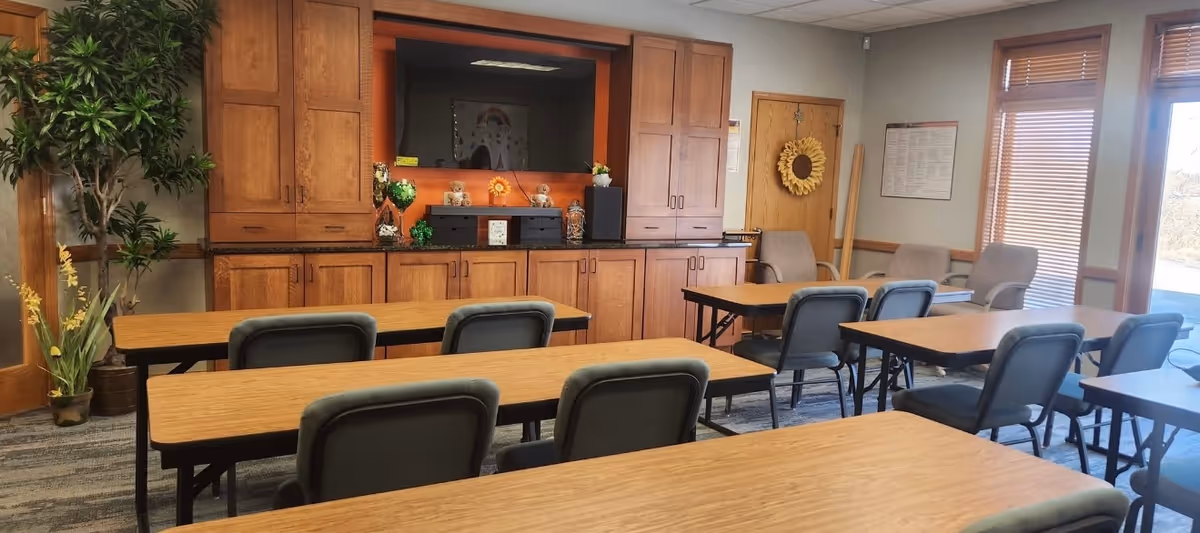 A spacious dining room with wooden tables, gray chairs, and a cabinetry wall behind.