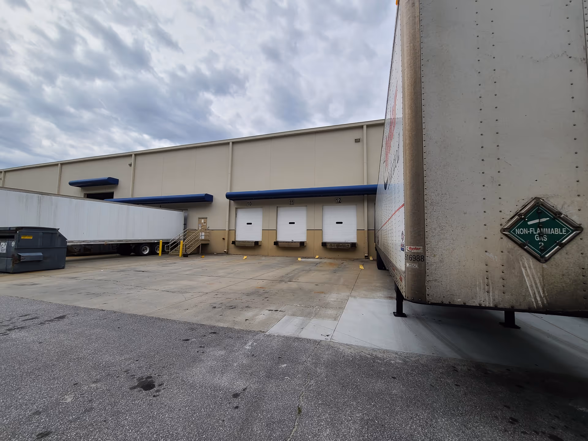 Industrial loading dock area with bay doors and a large semi-trailer.