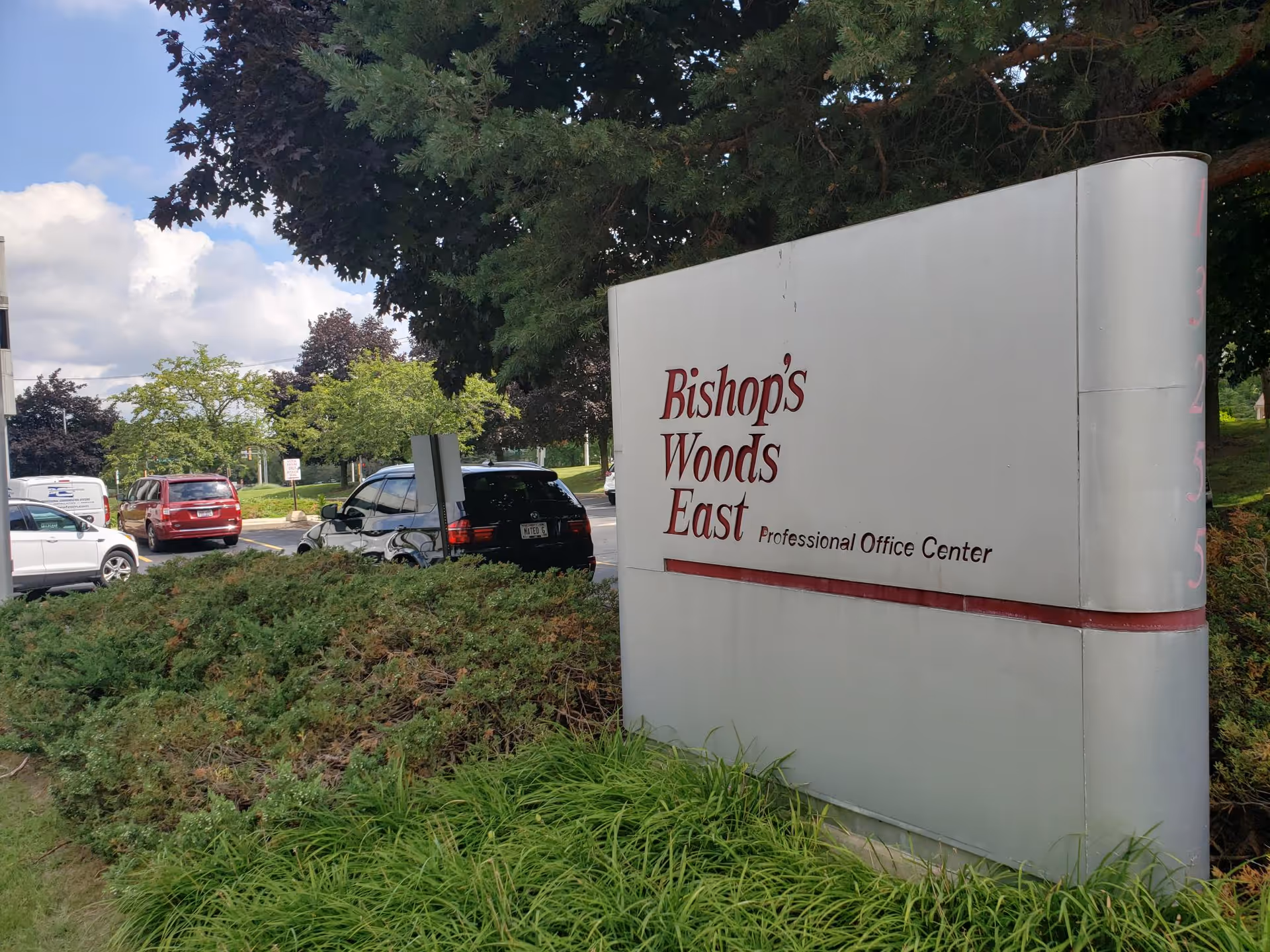 Exterior view of Bishop's Woods East Professional Office Center sign beside a parking lot.