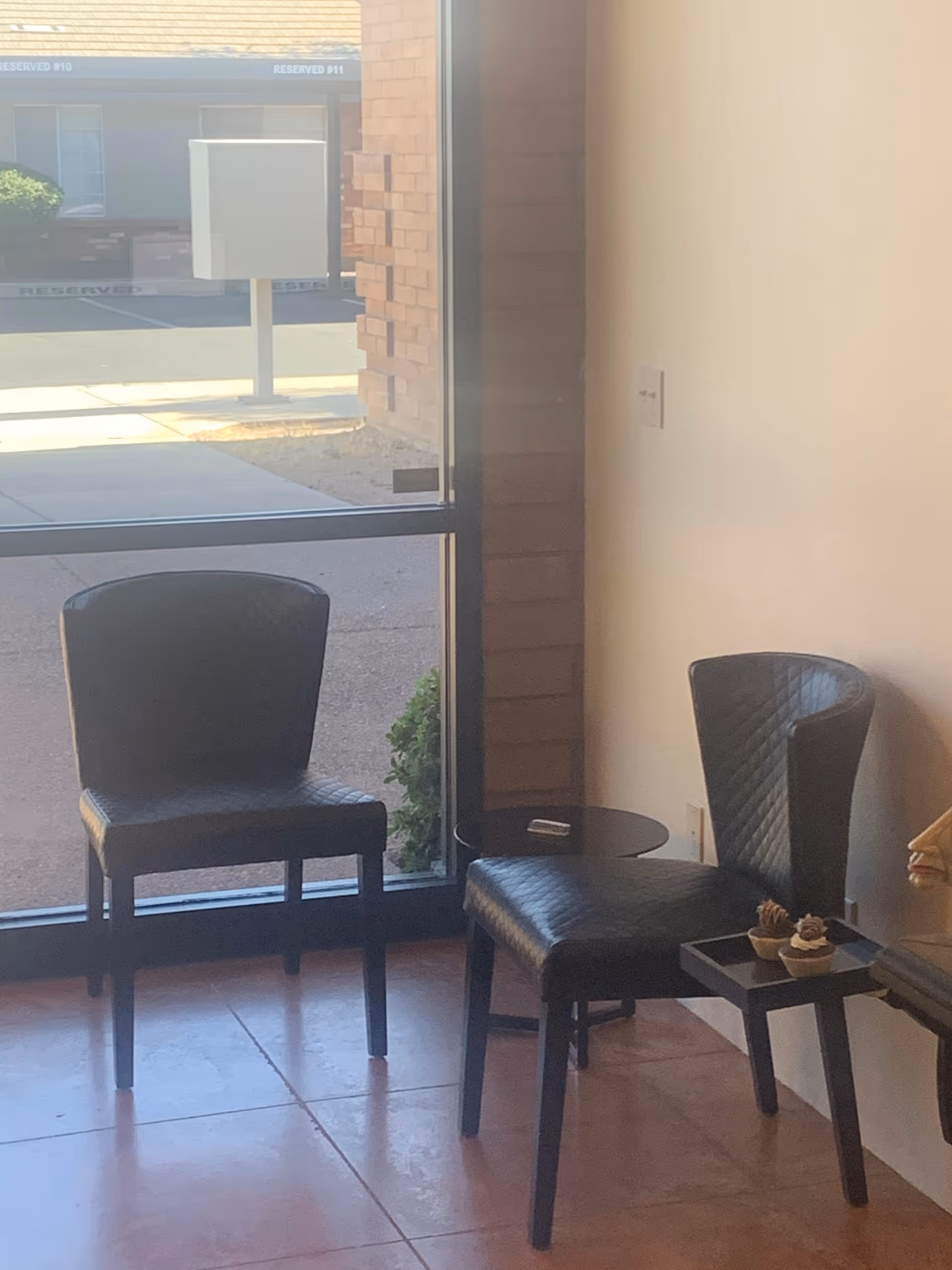 Bright interior seating area with two black leather chairs and a small table by a window.