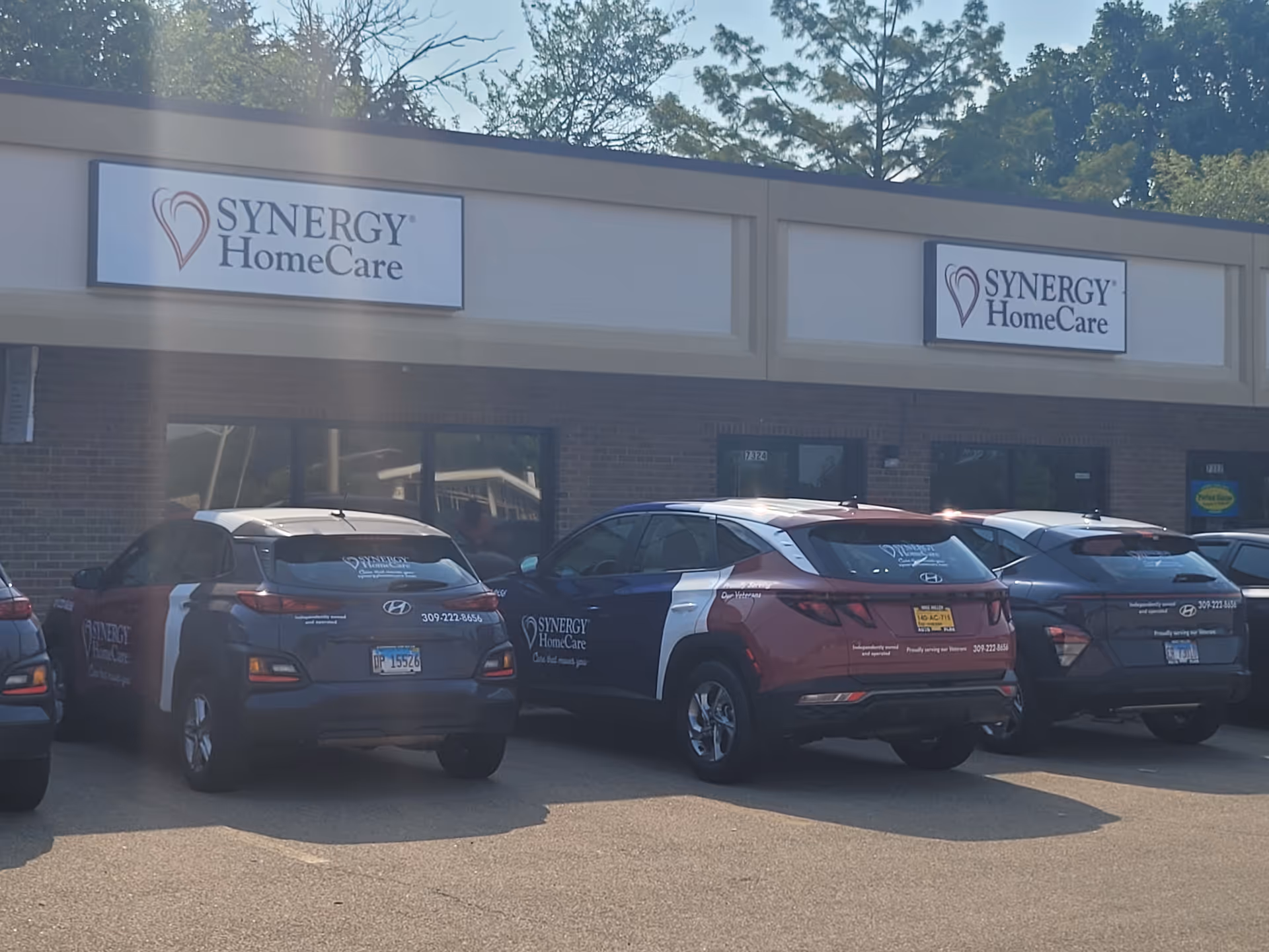 Exterior view of a Synergy HomeCare building with several parked cars in front.
