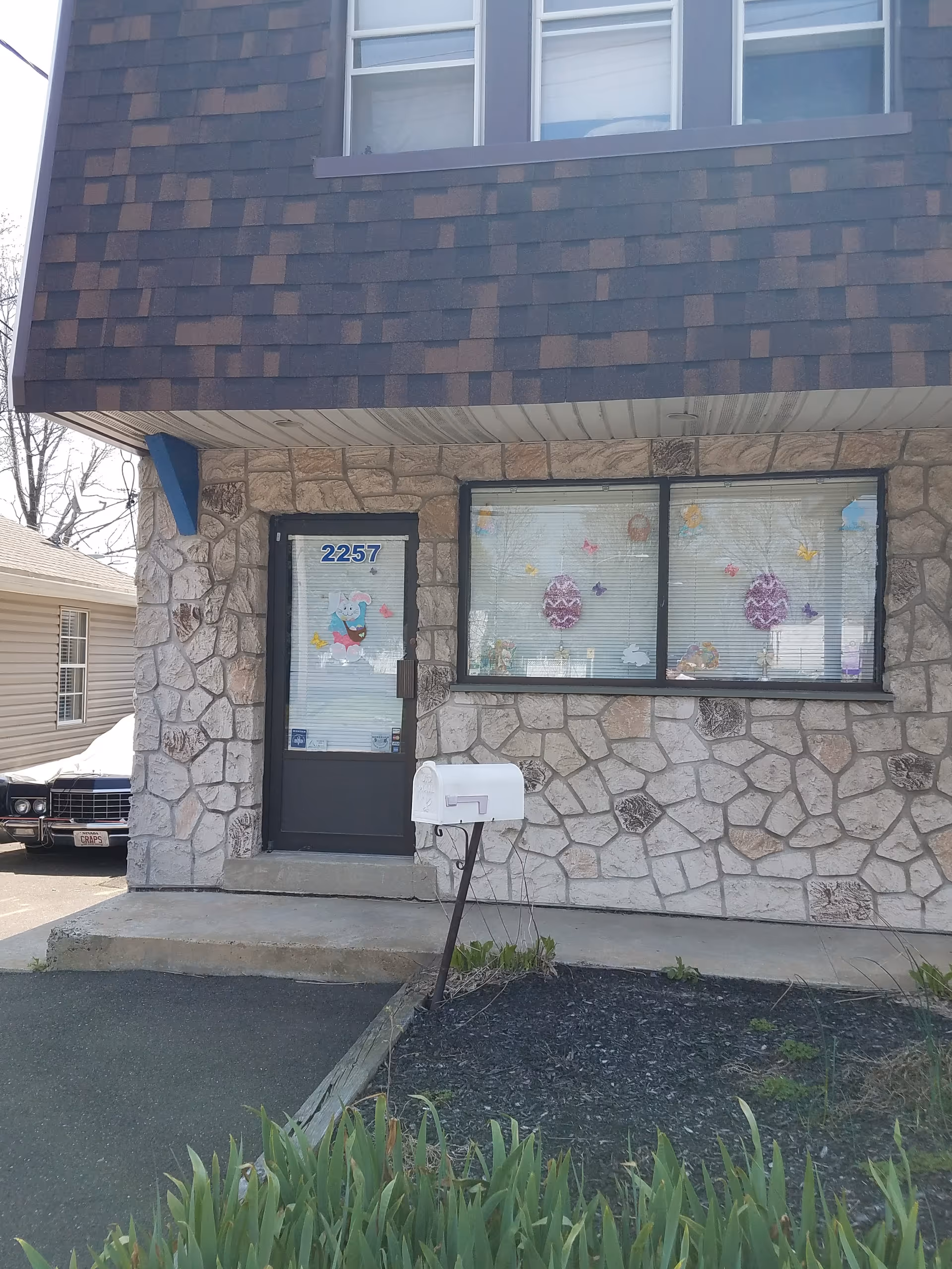 Stone-faced building exterior with front door, window displays, and a mailbox.