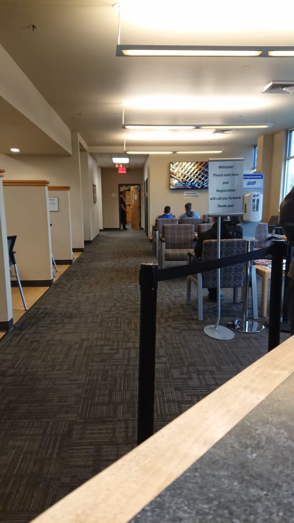 A senior living facility lobby with chairs and a hallway leading to offices.