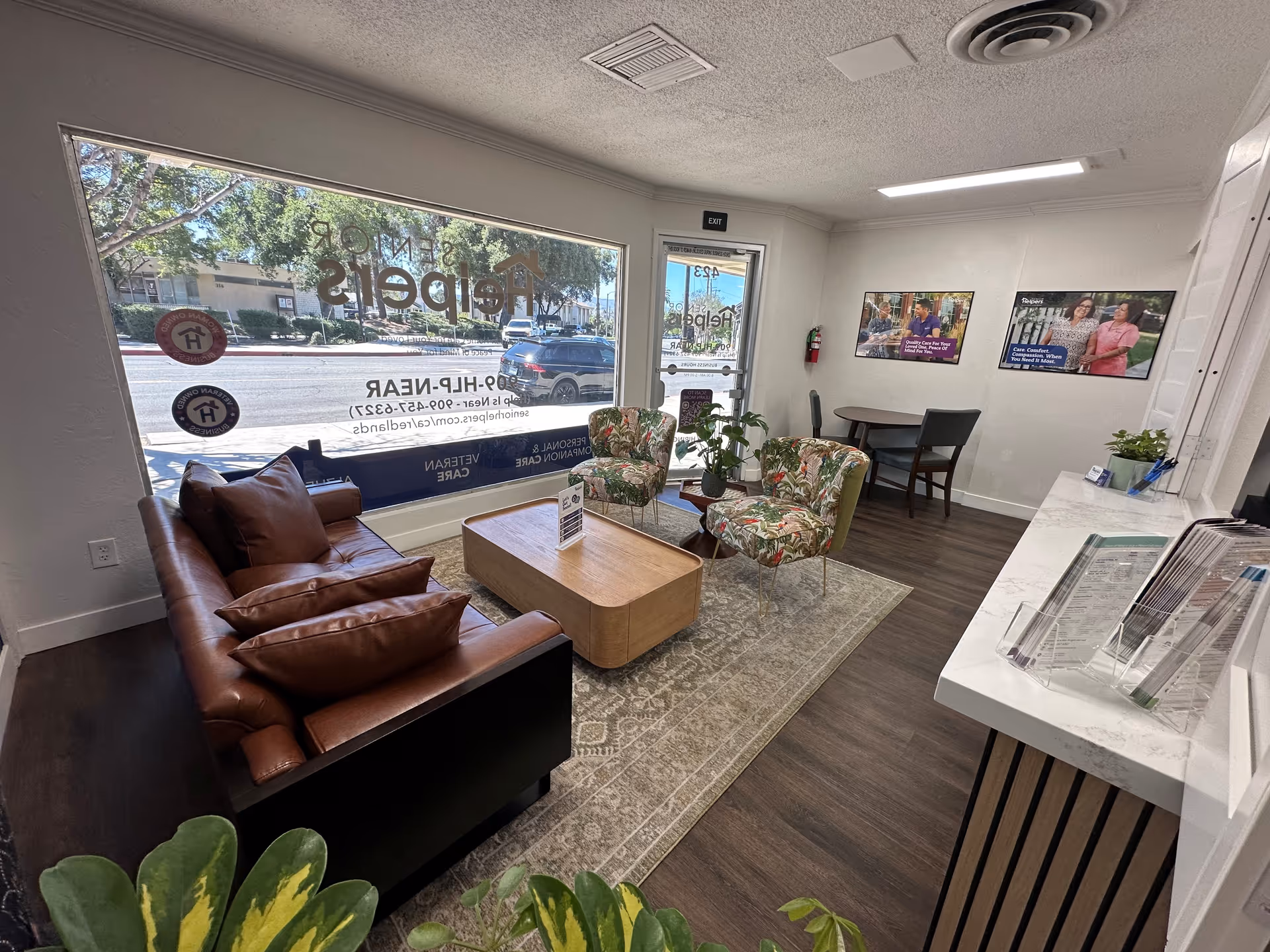 Cozy facility lobby with leather sofa, patterned chairs, coffee table, and reception desk.