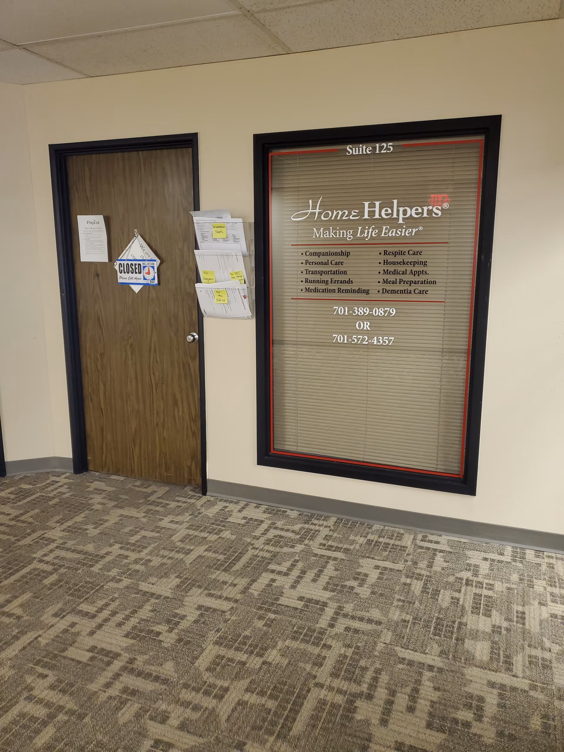 Interior hallway with a closed wooden door and a large Home Helpers sign in a window.