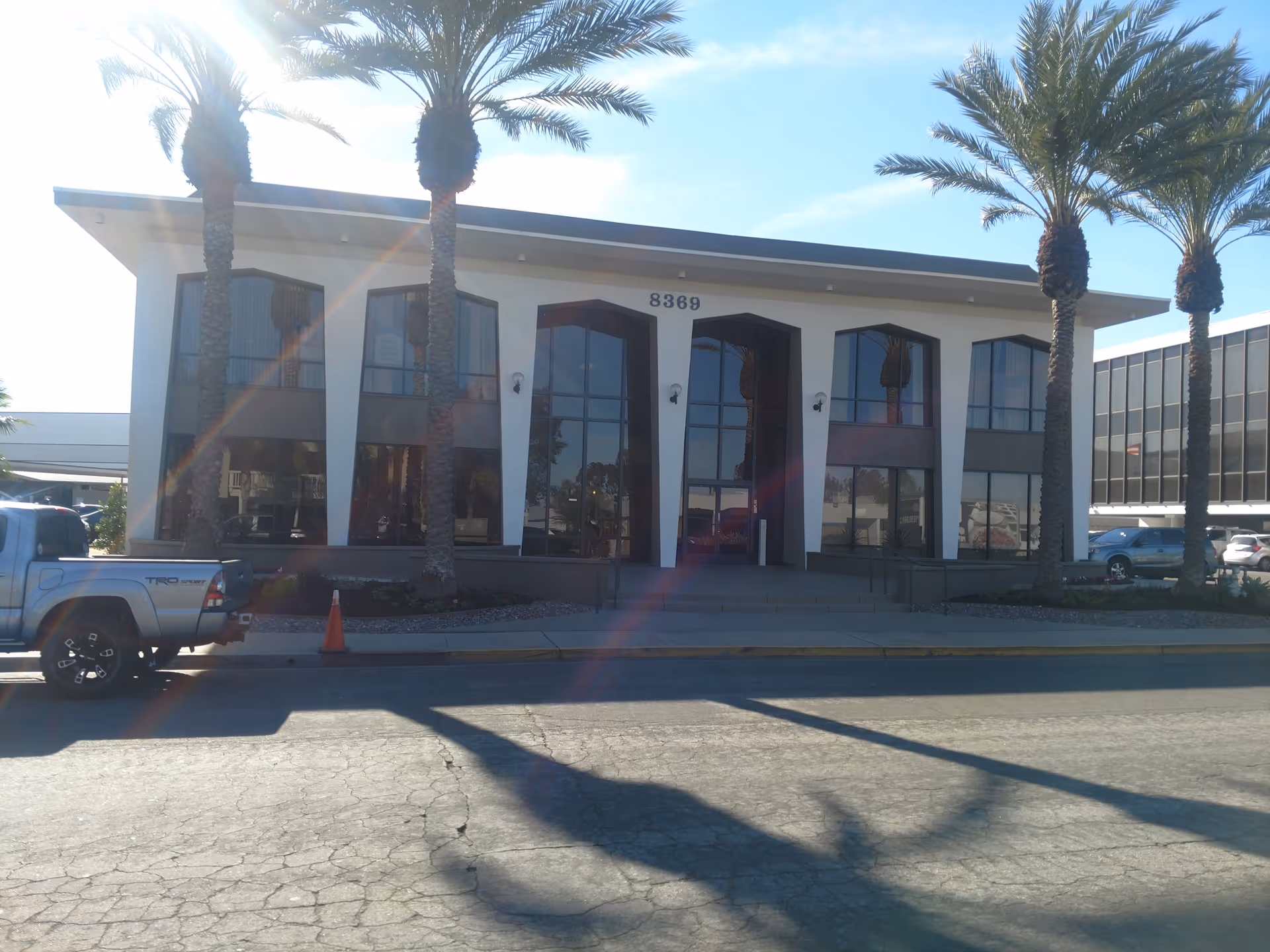 Exterior of a senior living facility with large windows and palm trees