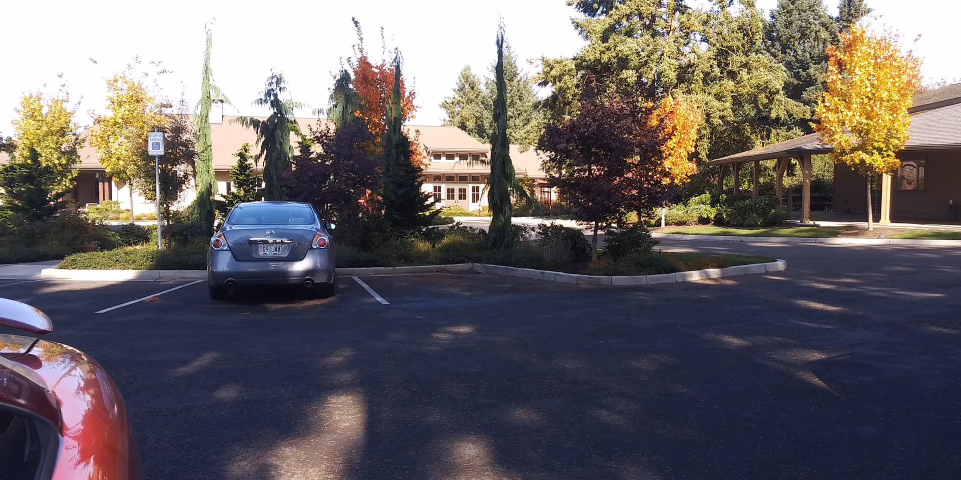 Exterior view of a parking lot with cars, trees, and a building entry.