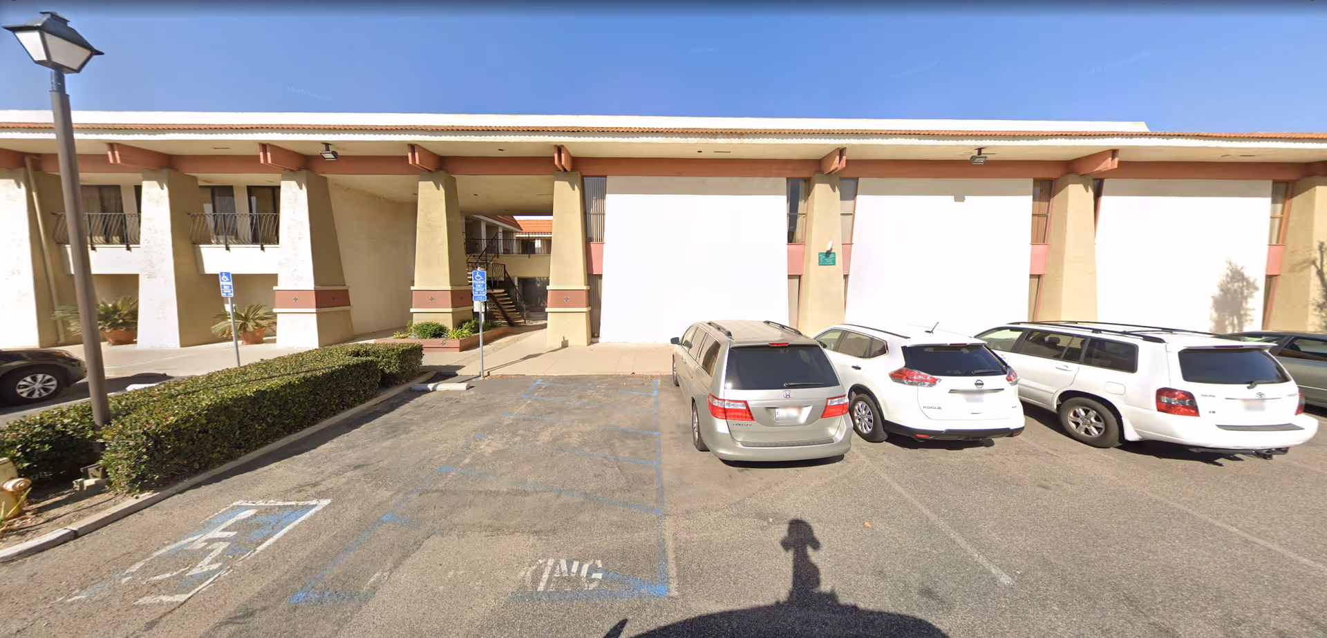 Exterior view of a senior living facility with parked cars and handicap spaces.