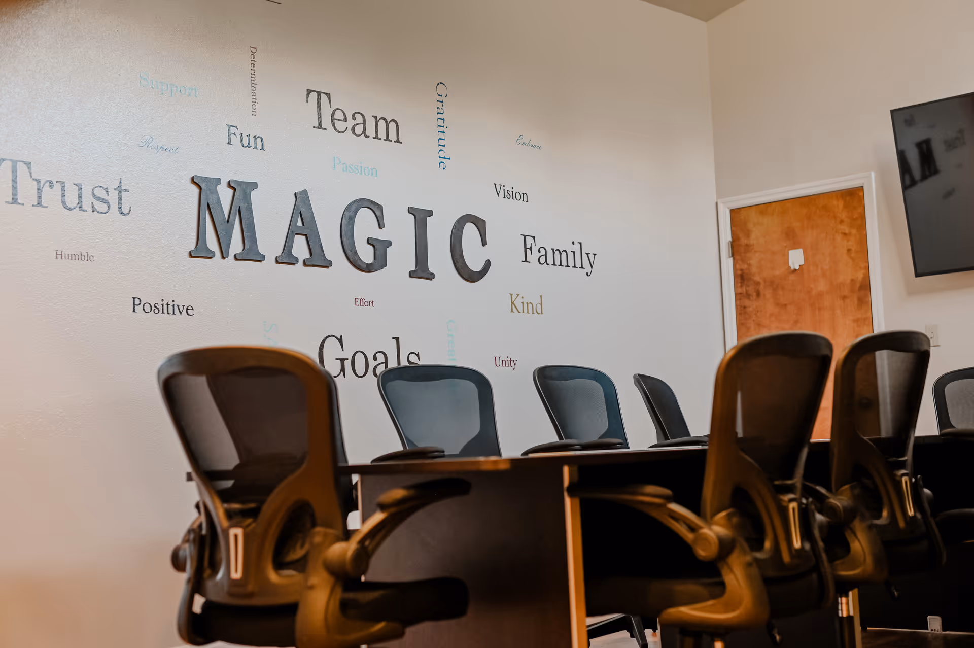 Conference room with a long table, office chairs, and word-wall art.