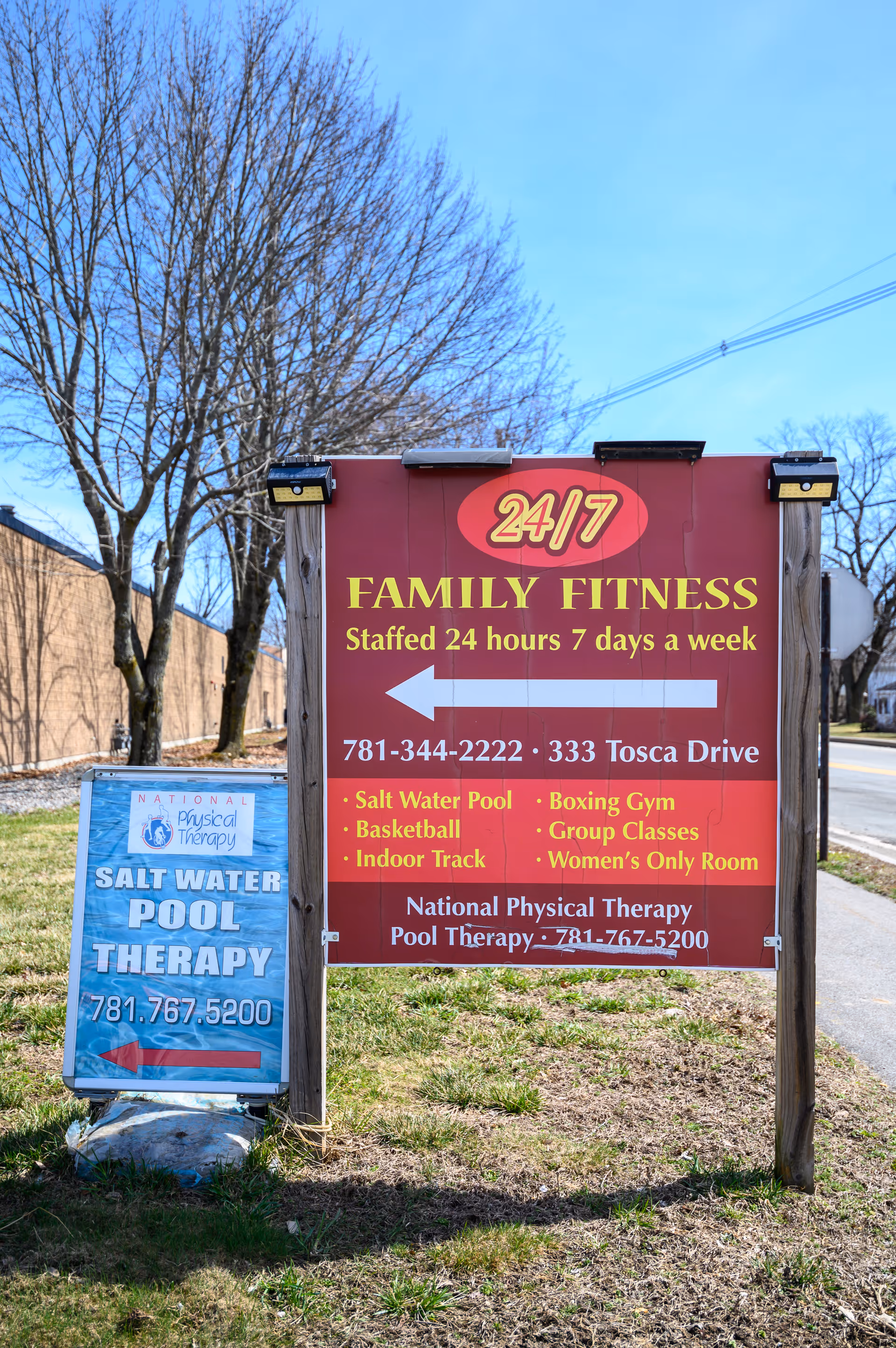 Two outdoor signs promote 24/7 fitness and salt water pool therapy at National Physical Therapy.