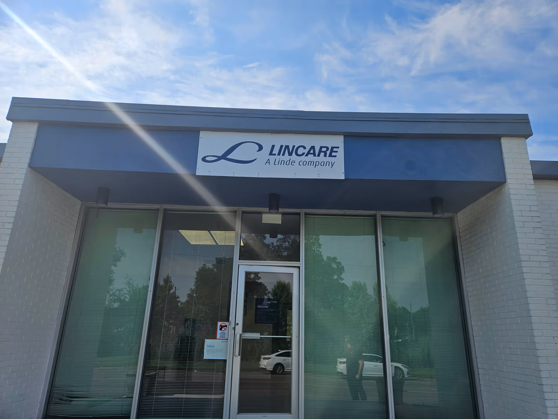 Front entrance of Lincare facility with glass doors and a blue sign overhead.