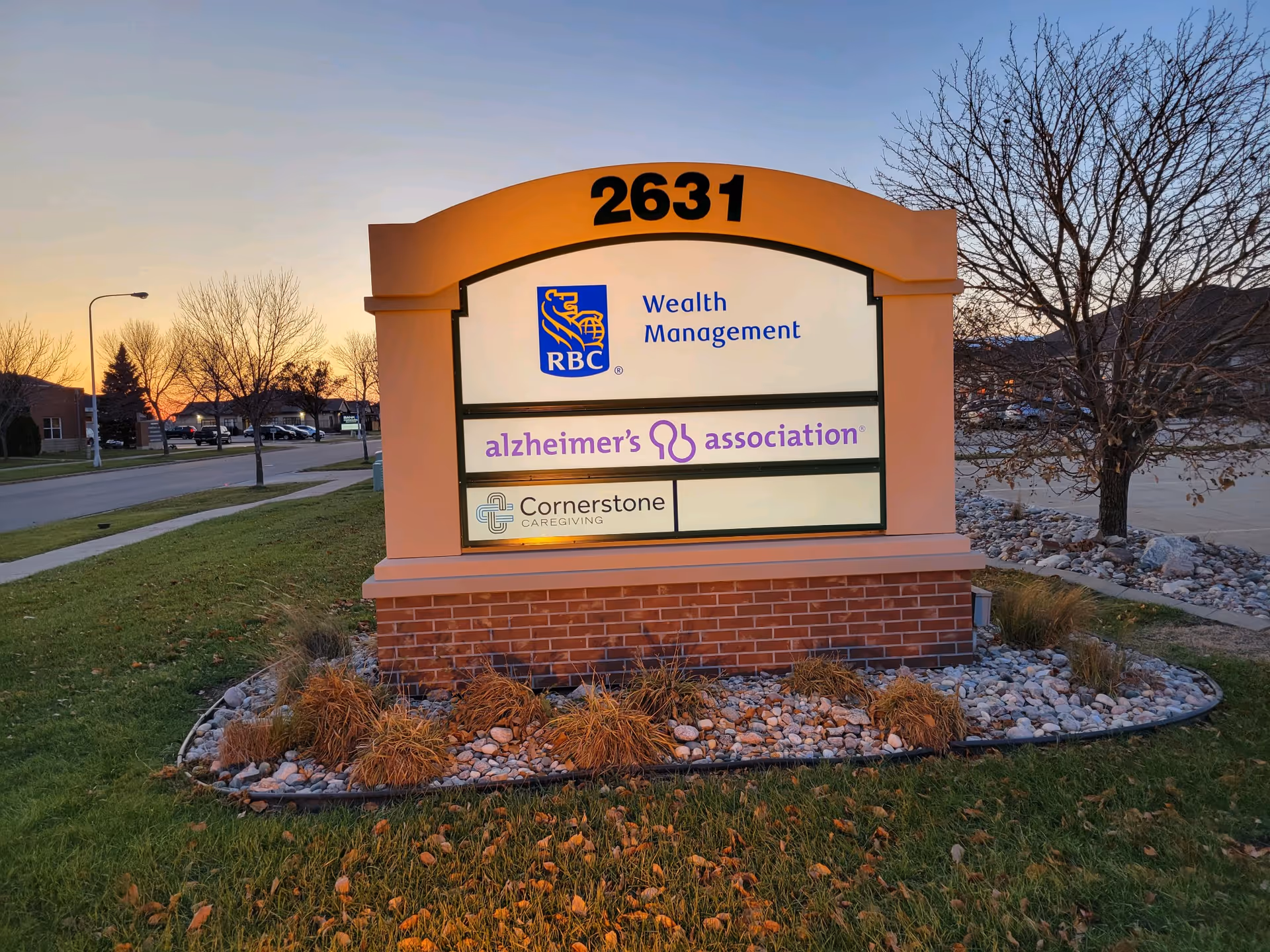 Exterior sign for Cornerstone Caregiving with logos, set in landscaped grounds.