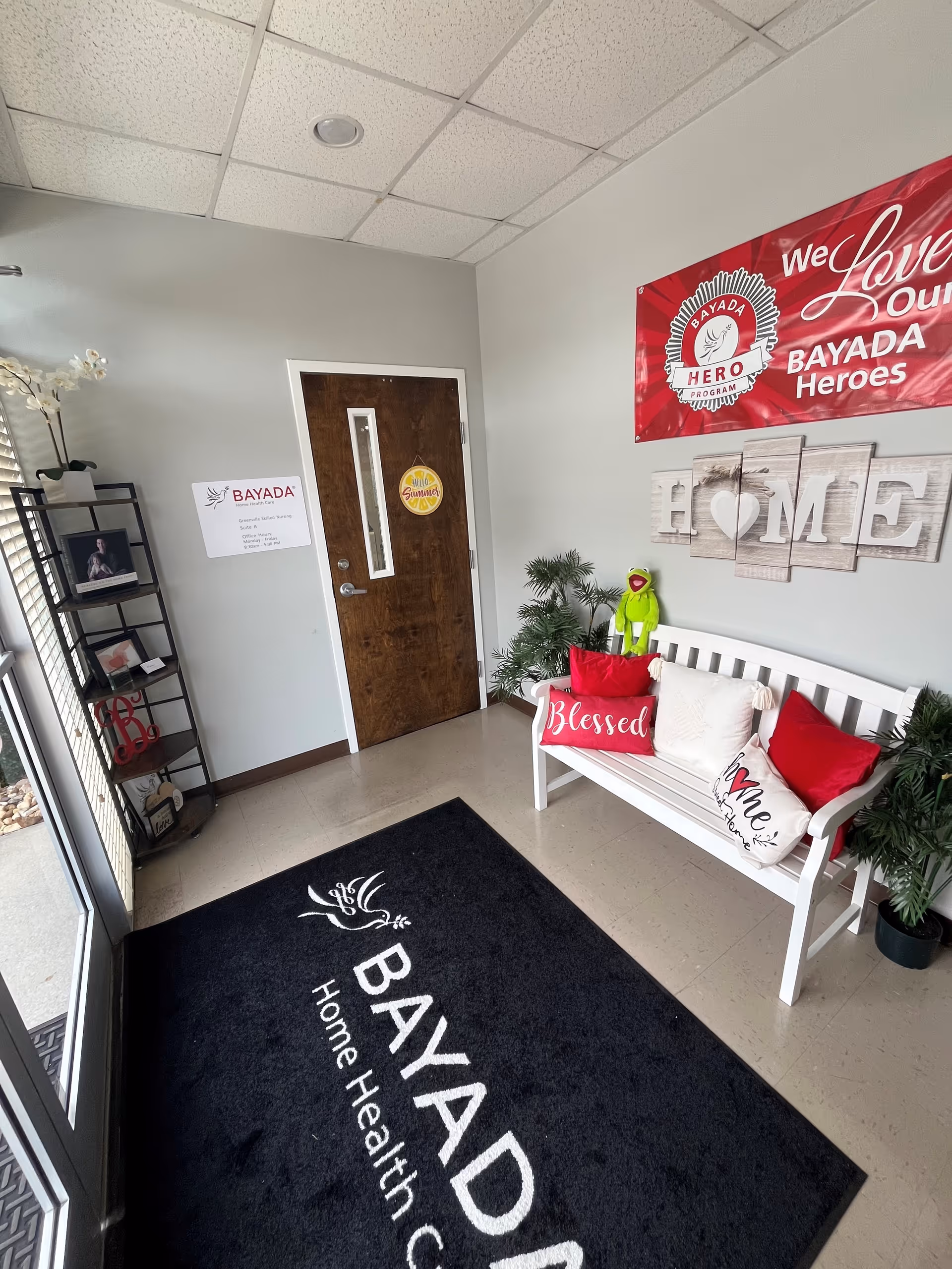 Interior lobby with a bench, door, plants, and BAYADA signage.
