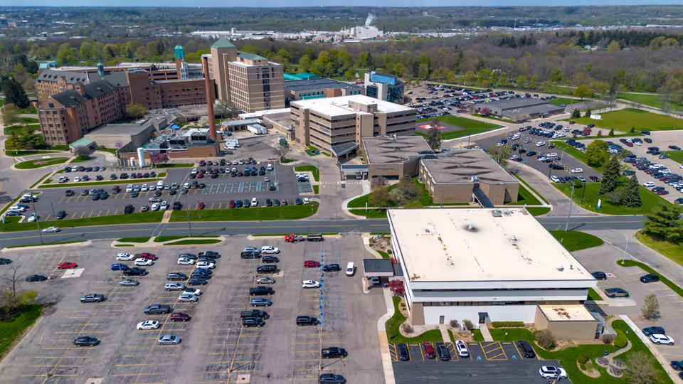 Aerial view of Total Spectrum ABA campus: multiple buildings, large parking lots, and surrounding trees.