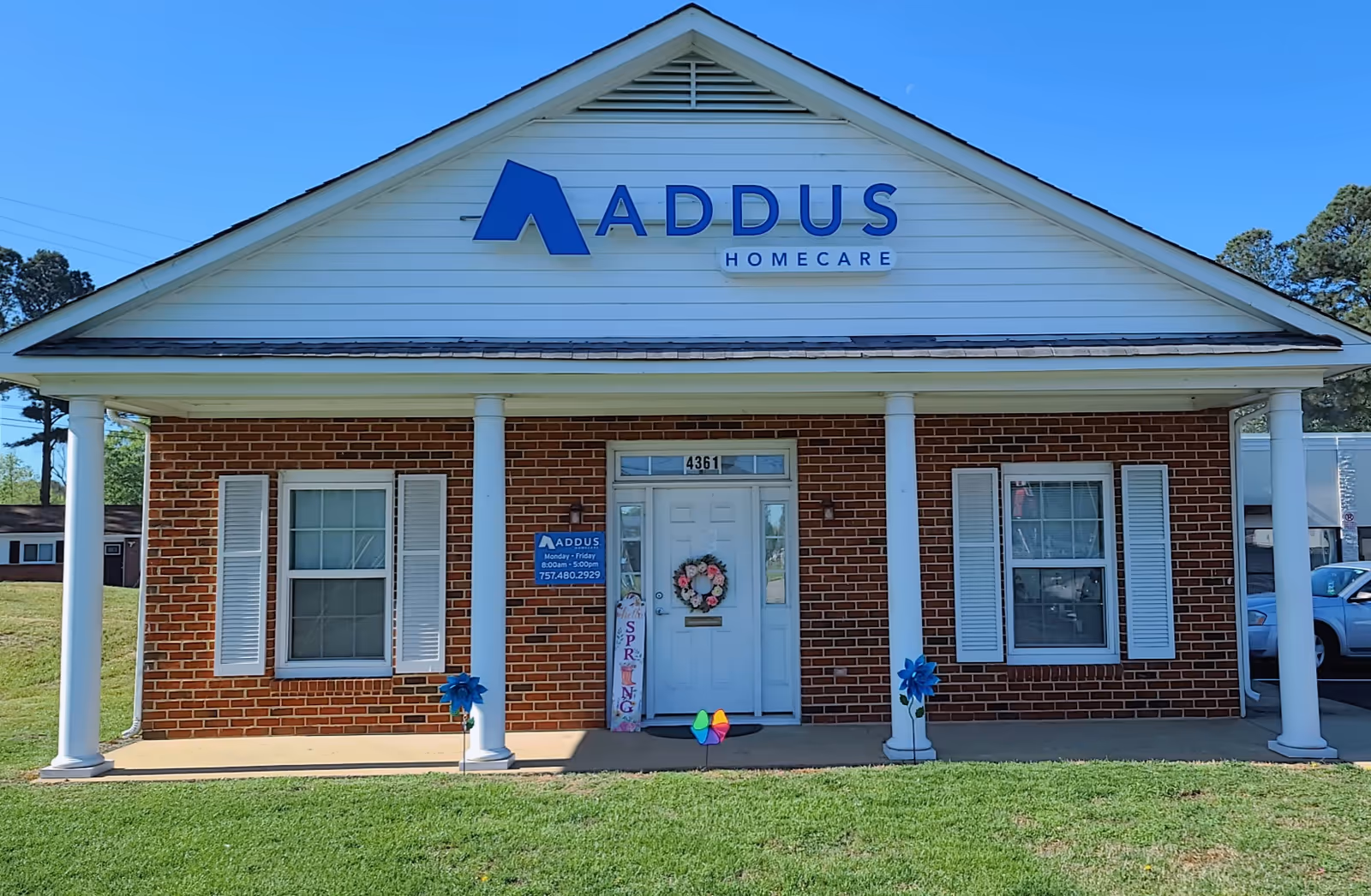 Front view of a brick Addus HomeCare facility with white columns and a wreath.
