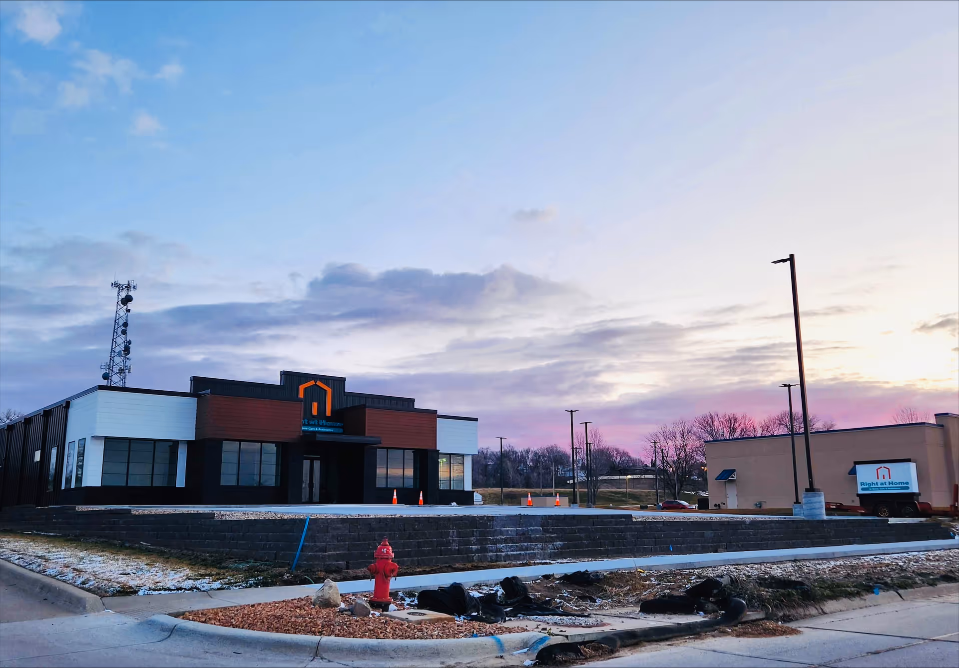 Exterior view of a modern Right at Home facility with a parking area and sign.