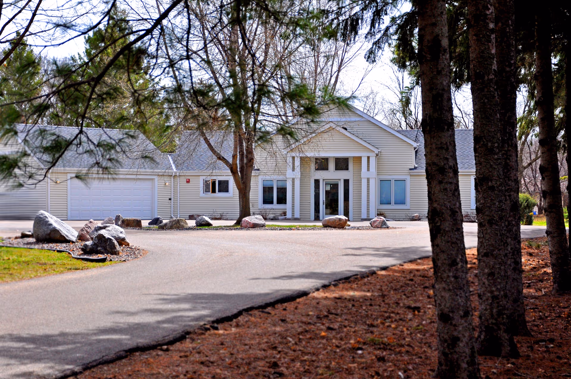 Exterior view of a single-story Homeward Bound Inc facility with a driveway and trees.