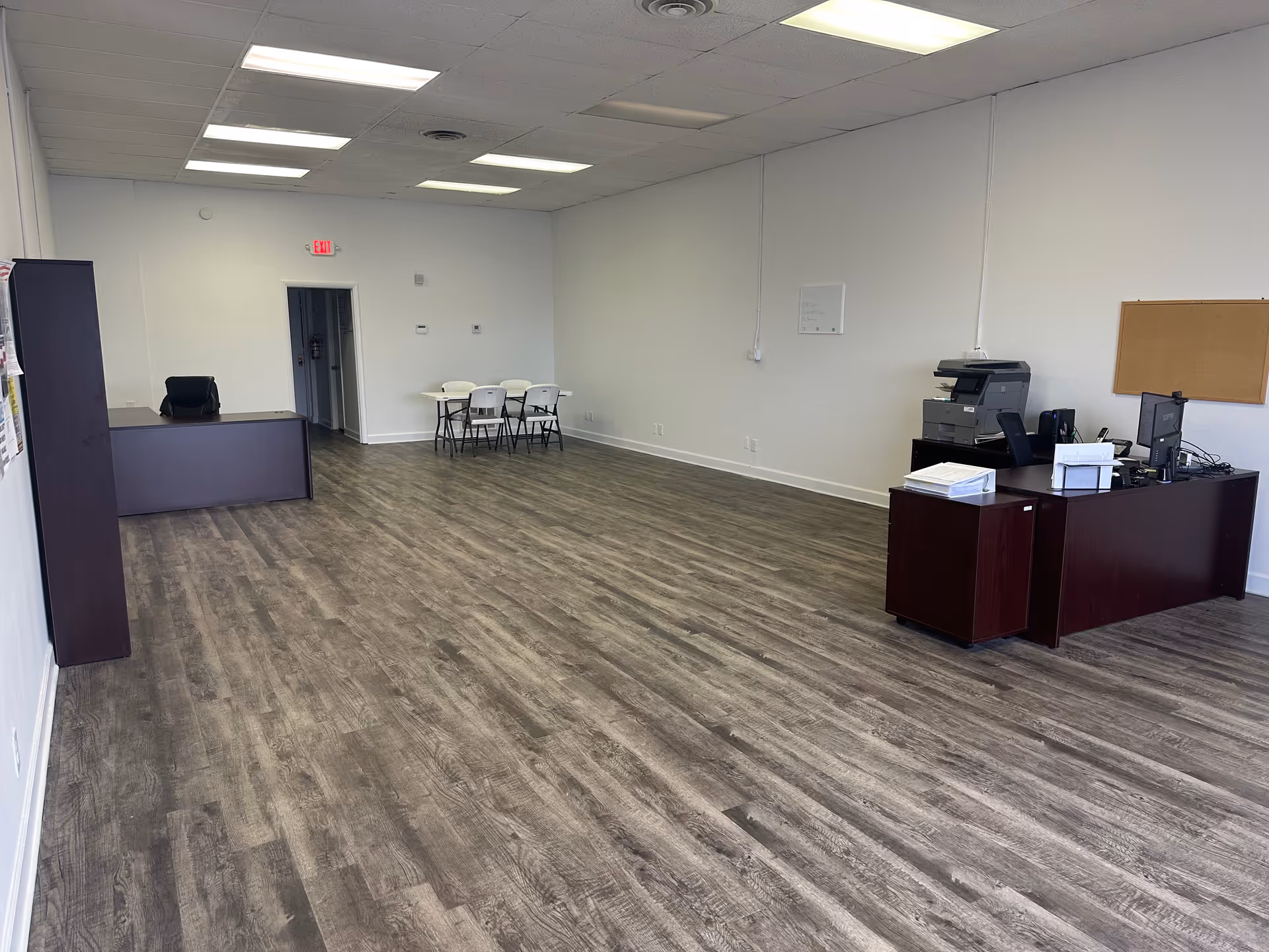 Wide, empty reception area with a desk, copier, and small seating table.