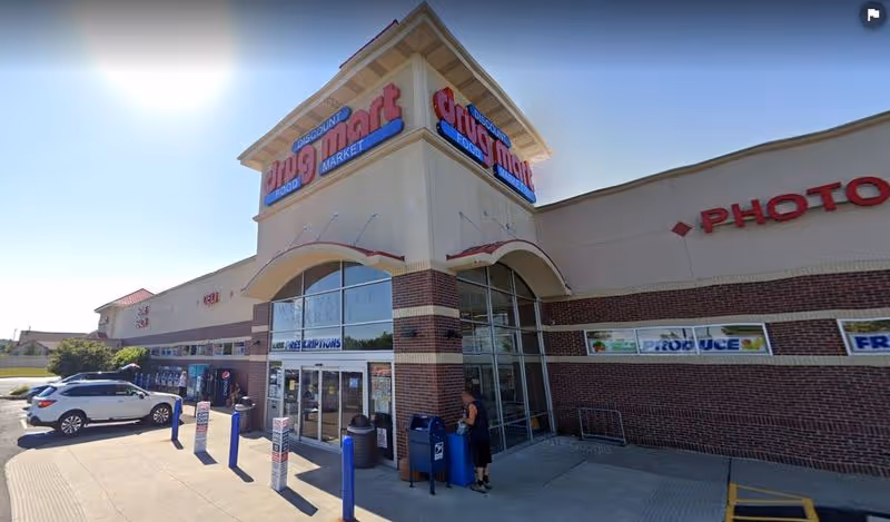 Wide exterior view of Discount Drug Mart storefront with brick facade and glass doors.