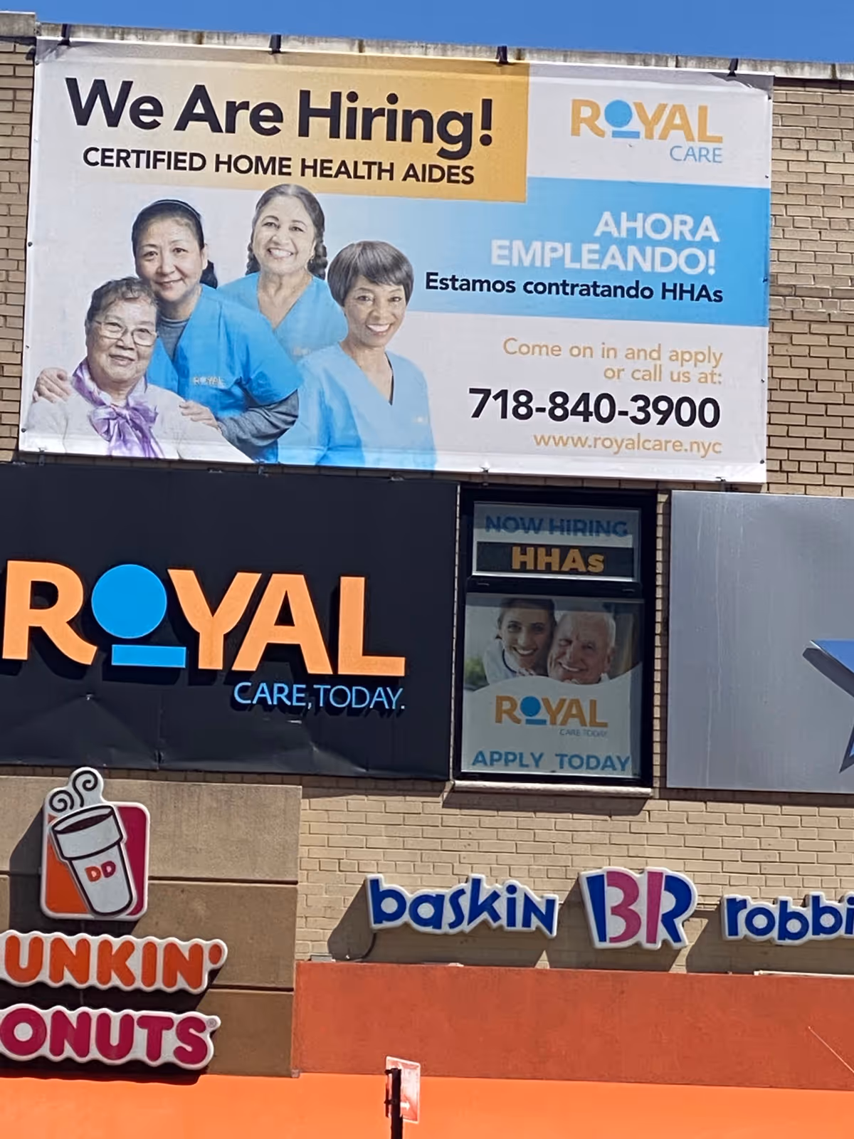 Exterior view of Royal Care building with a large We Are Hiring banner featuring nurses.