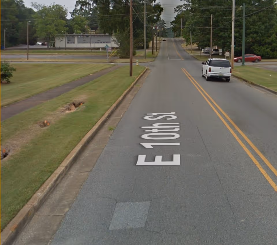 Wide street with painted street name E North St, grassy medians, parked cars, and trees.