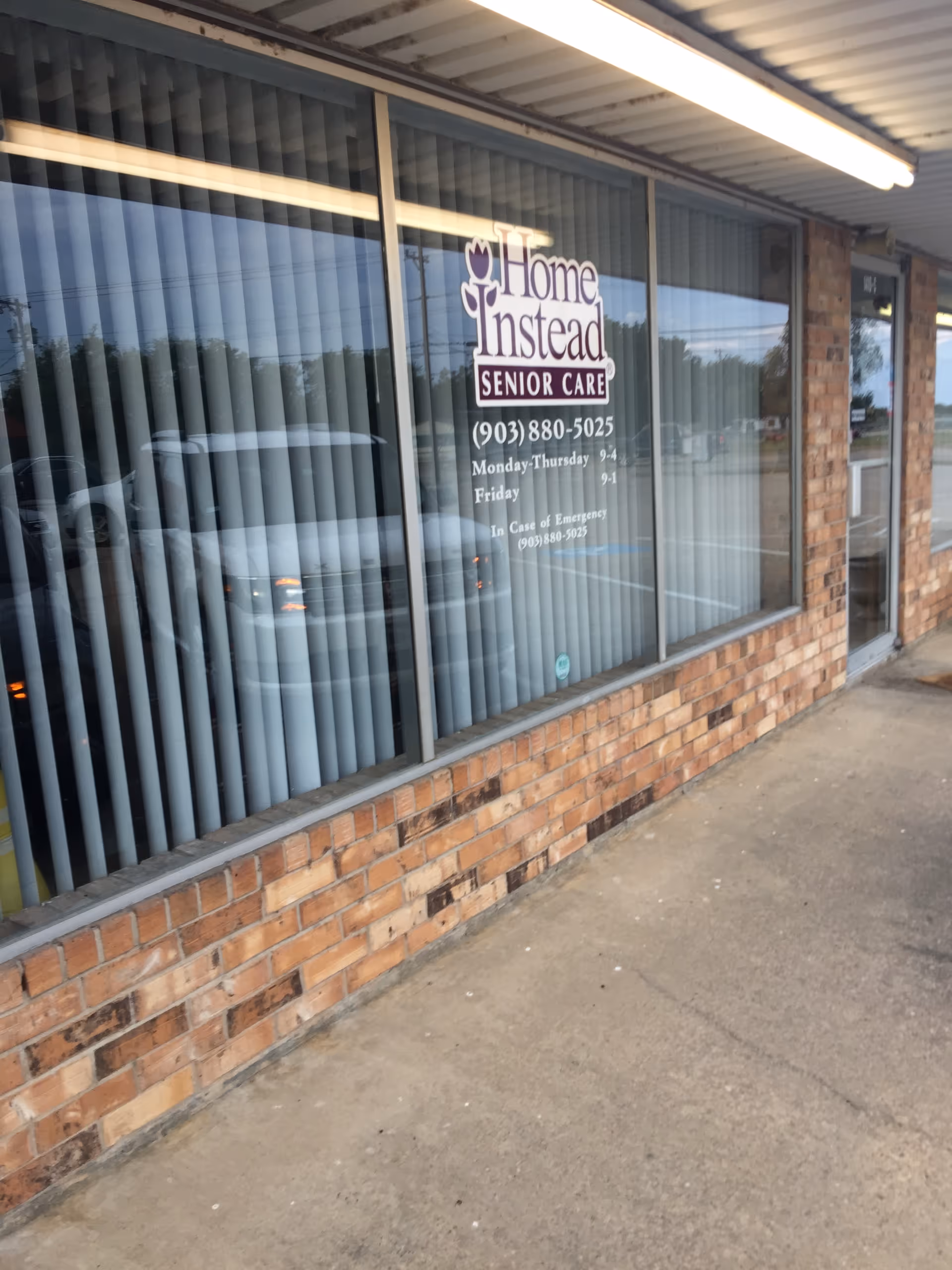 Brick storefront with large glass windows displaying Home Instead Senior Care signage.