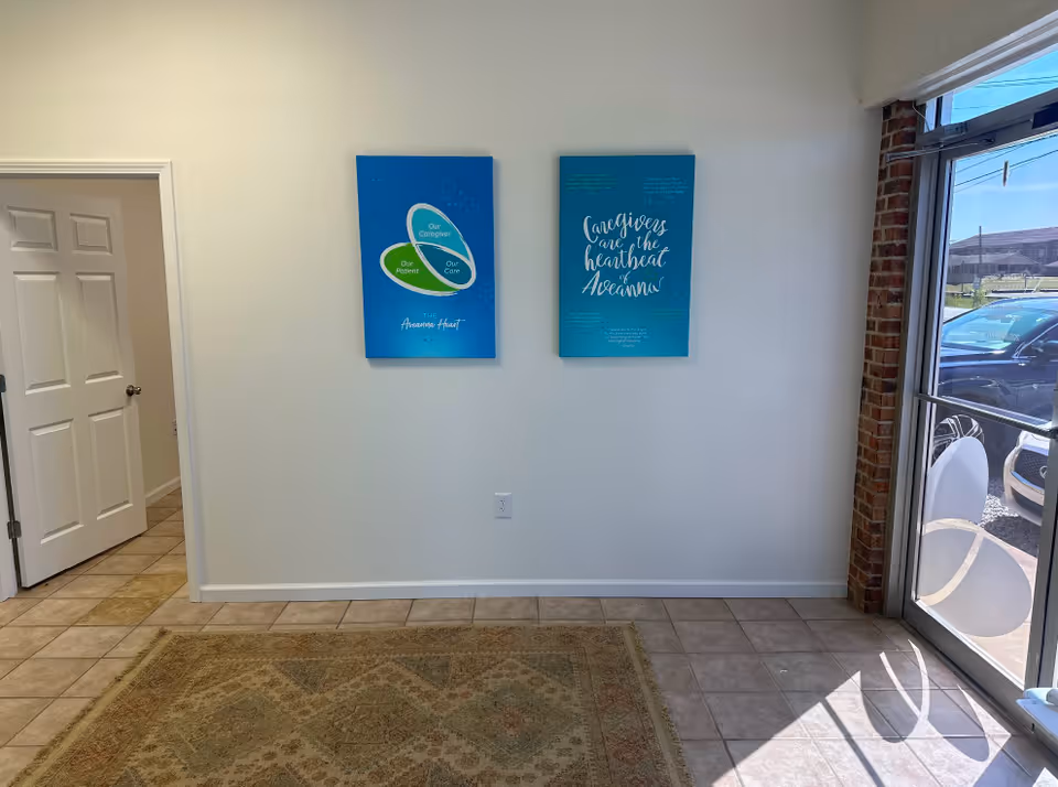 Bright lobby area with two blue posters on a white wall, glass entrance on right.