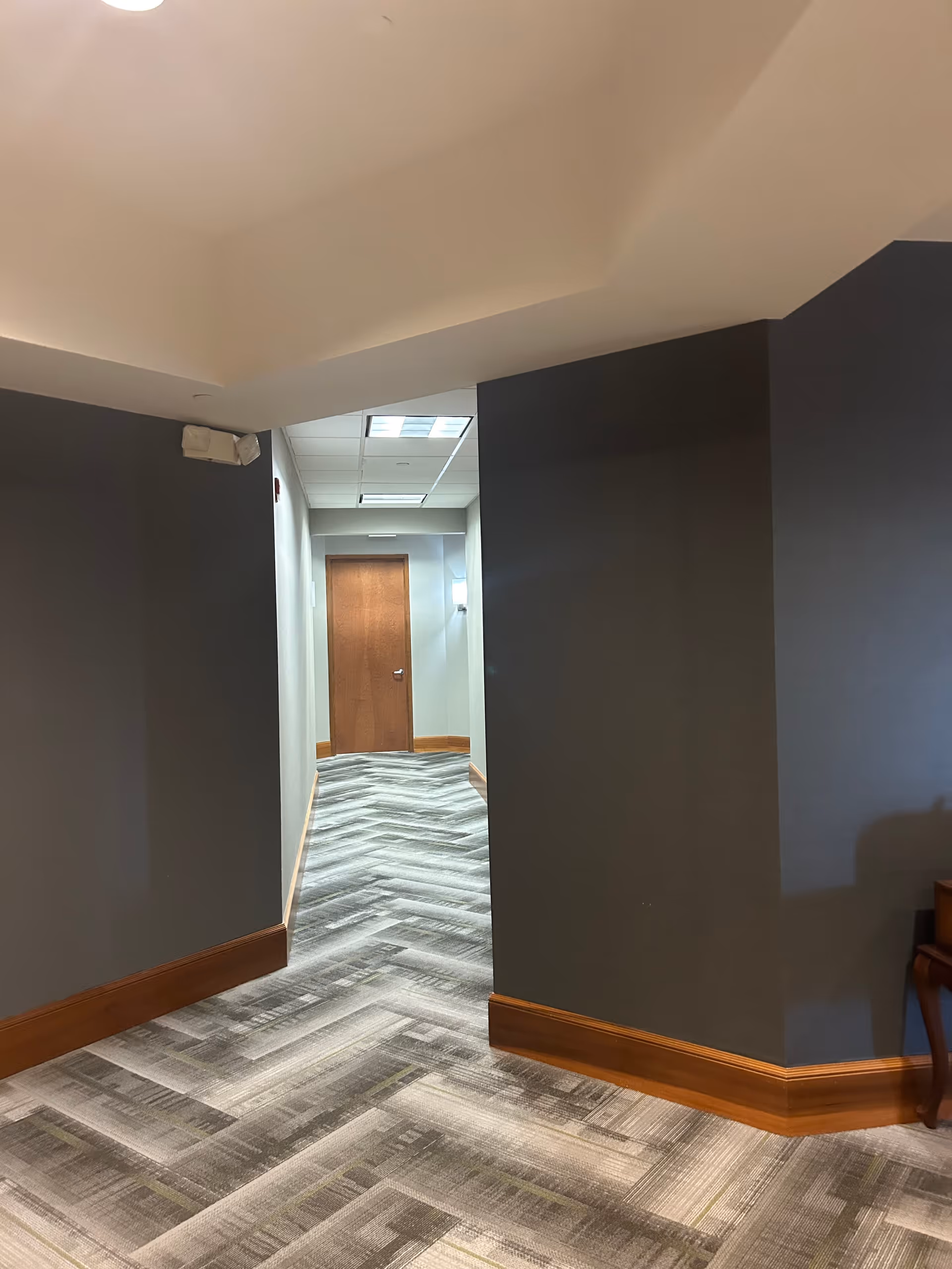 Interior hallway in a senior living facility with gray walls and a wooden door.