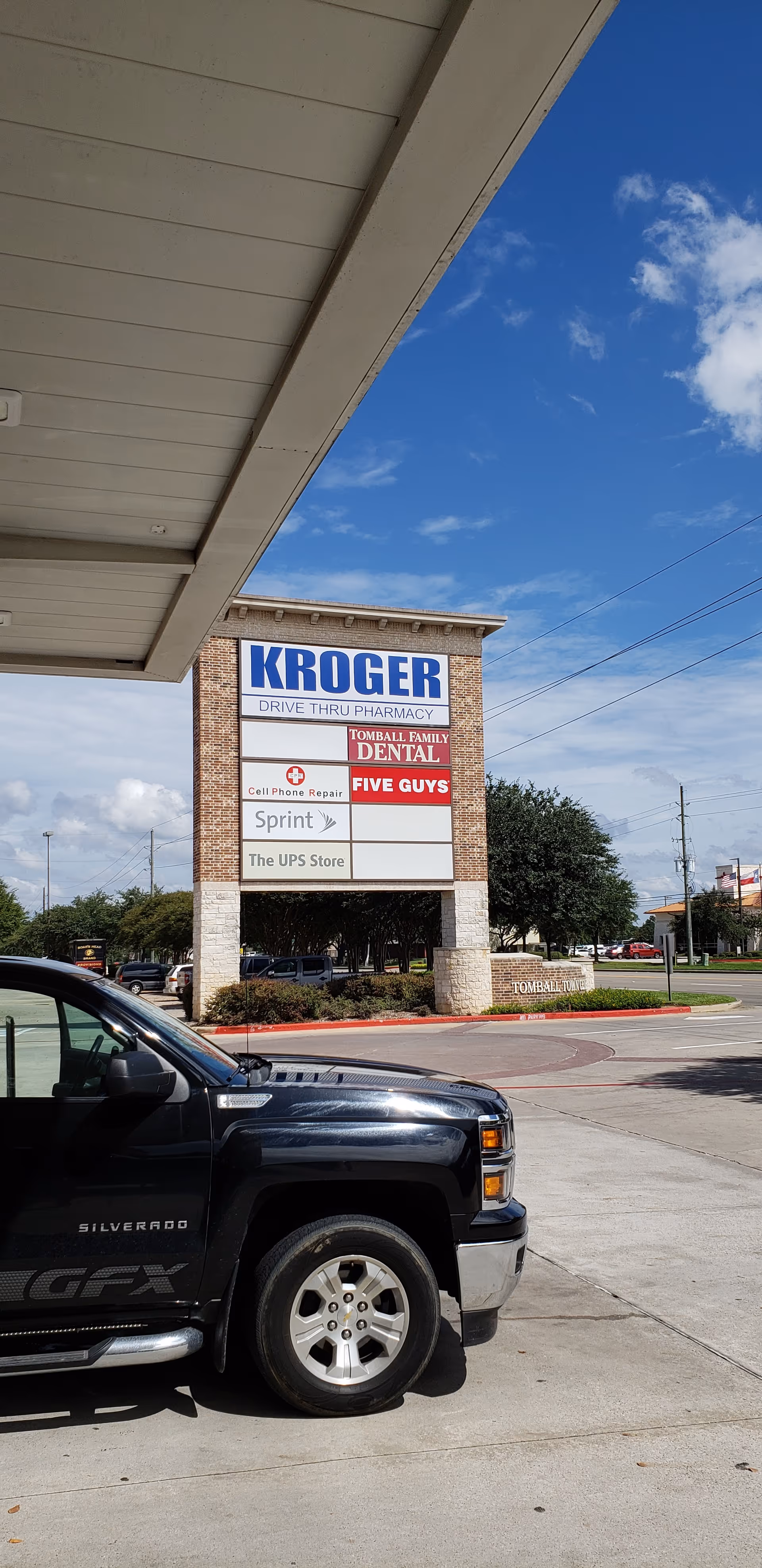 A Kroger storefront sign with drive-thru pharmacy visible in a parking lot.