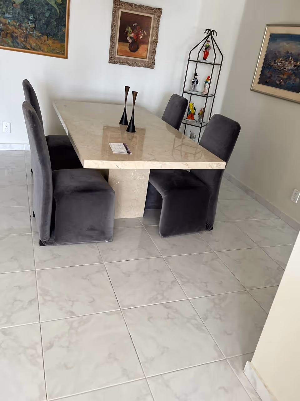 A marble dining table with six gray upholstered chairs in a bright dining area.