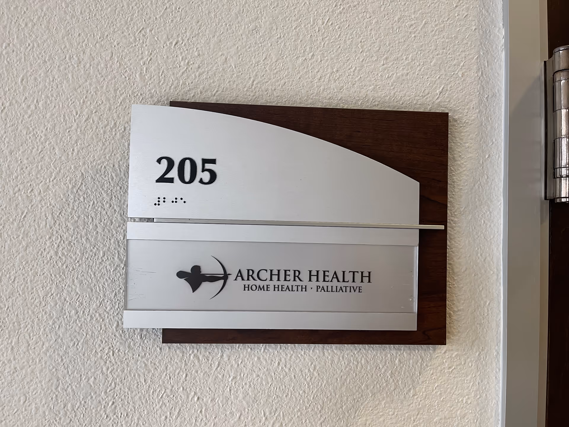 Interior wall sign displaying room 205 and Archer Health logo with company name.