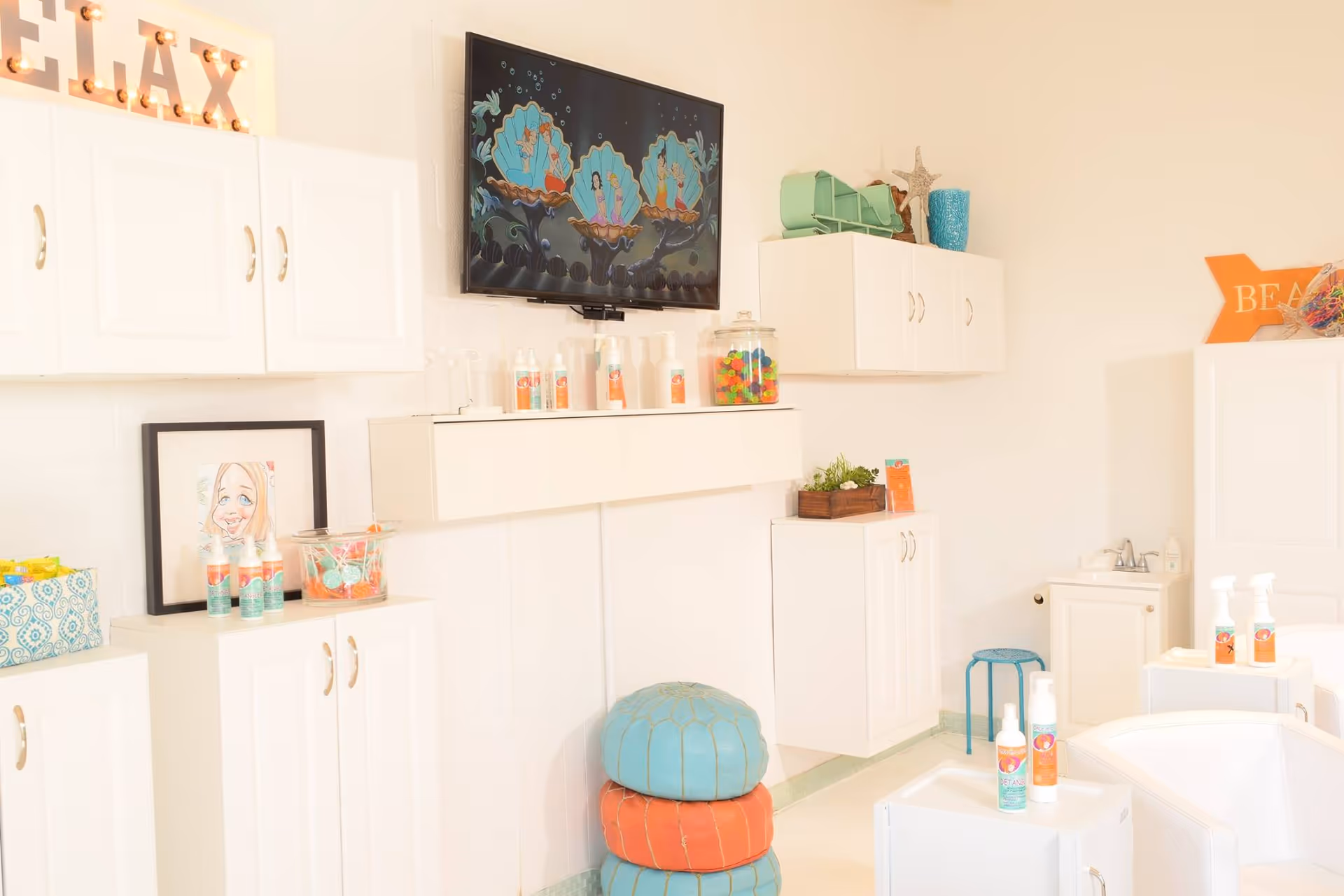 Bright white treatment room with cabinets, a wall TV, and colorful cushions on the floor.