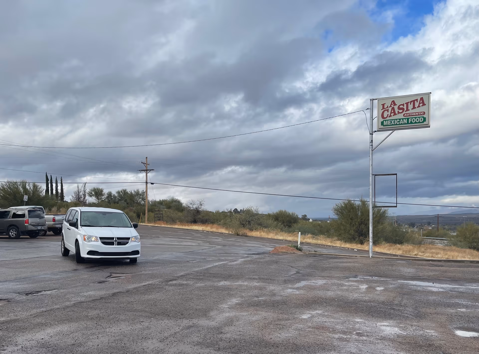 Parking lot with a white van and La Casita Mexican Food sign under a cloudy sky