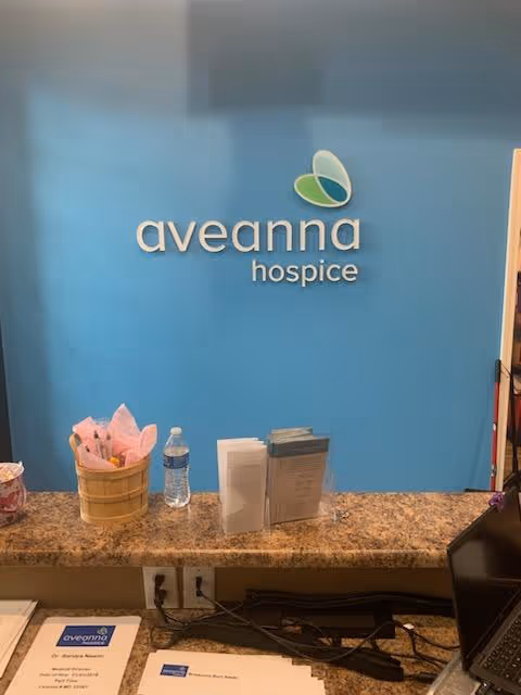 Reception desk with blue wall, Aveanna Hospice sign, brochures and water bottle.