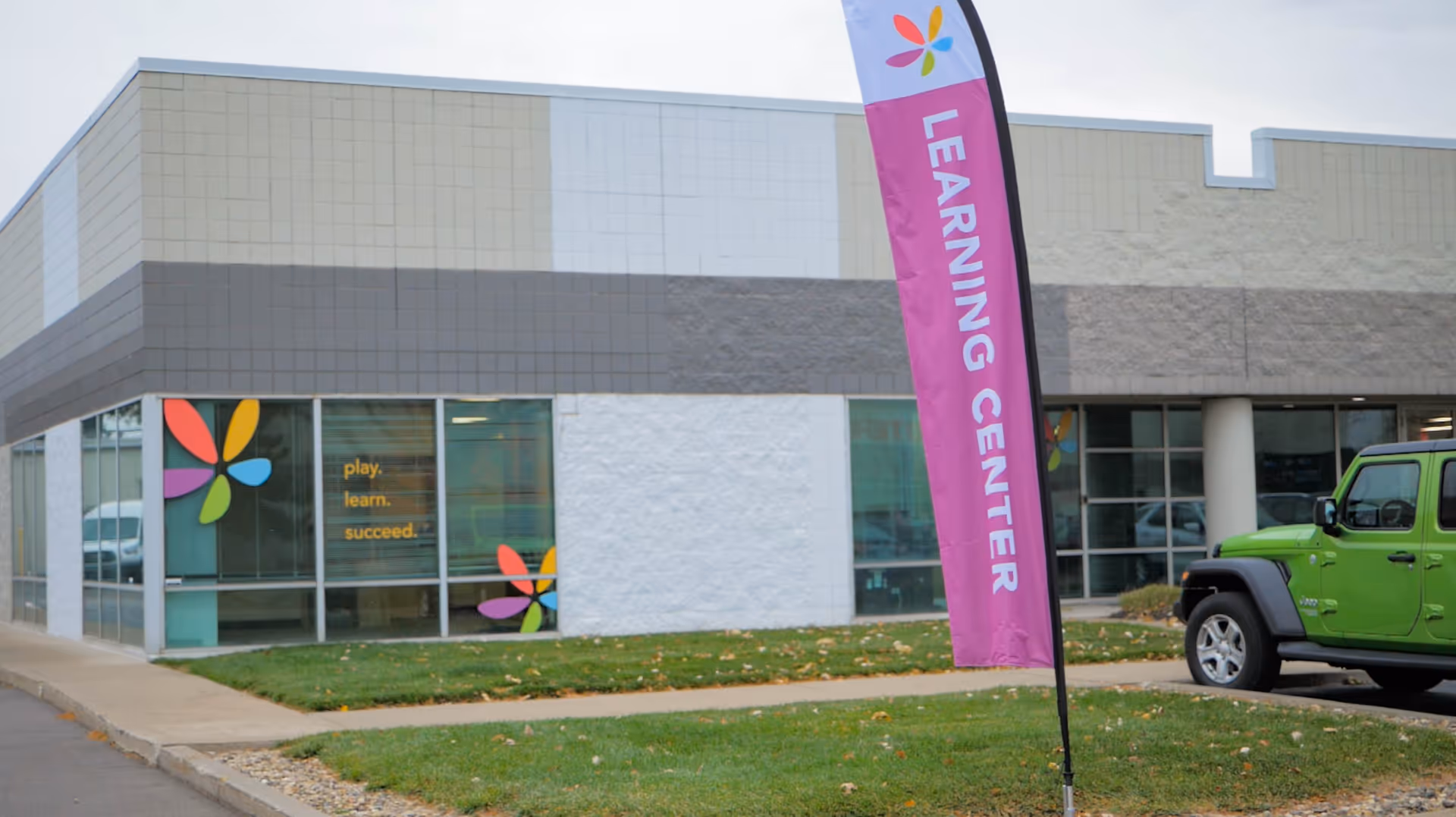 Exterior of a colorful learning center building with a tall pink banner reading Learning Center.
