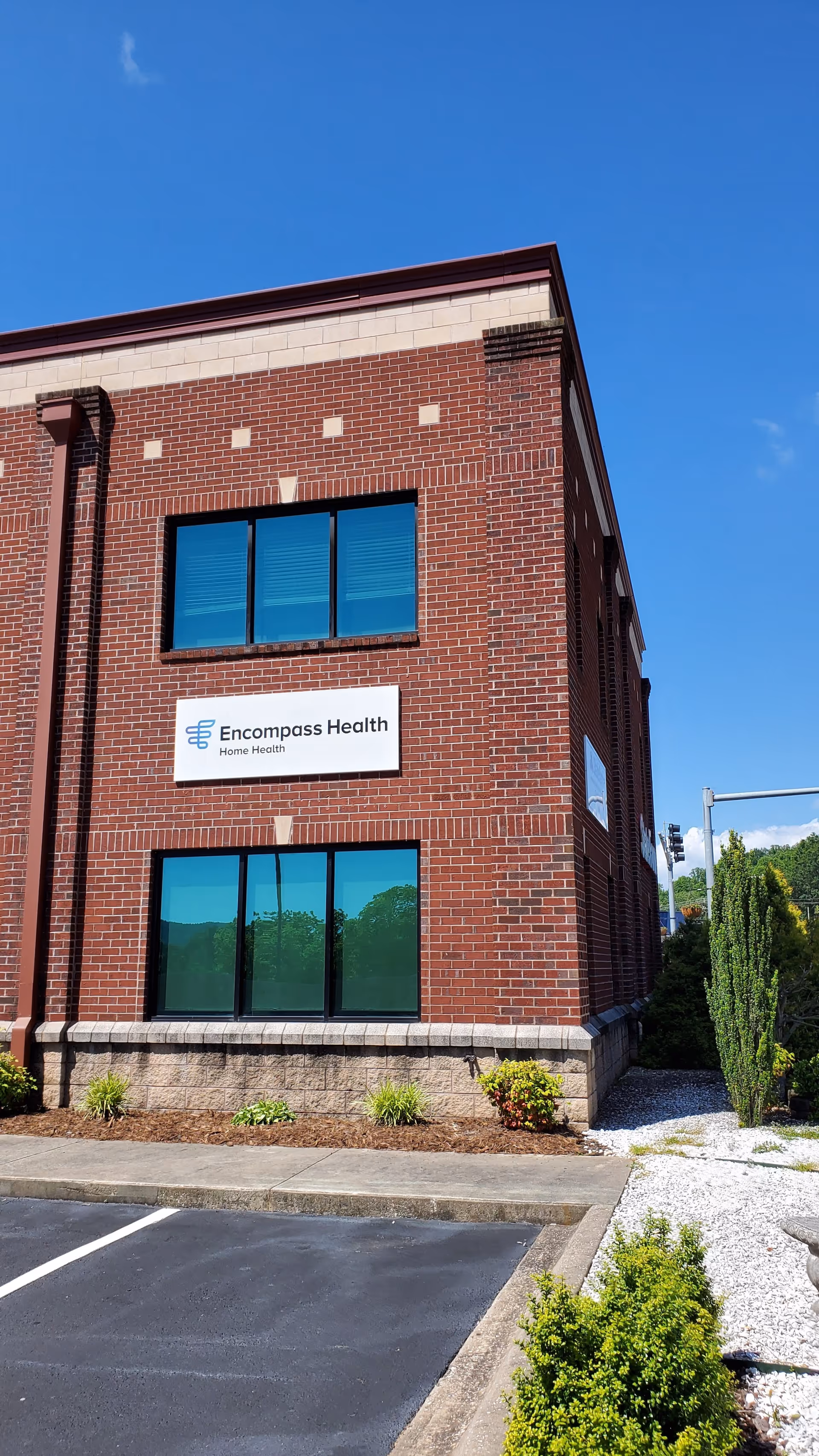 Brick Encompass Health Home Health building exterior with sign and blue-tinted windows.
