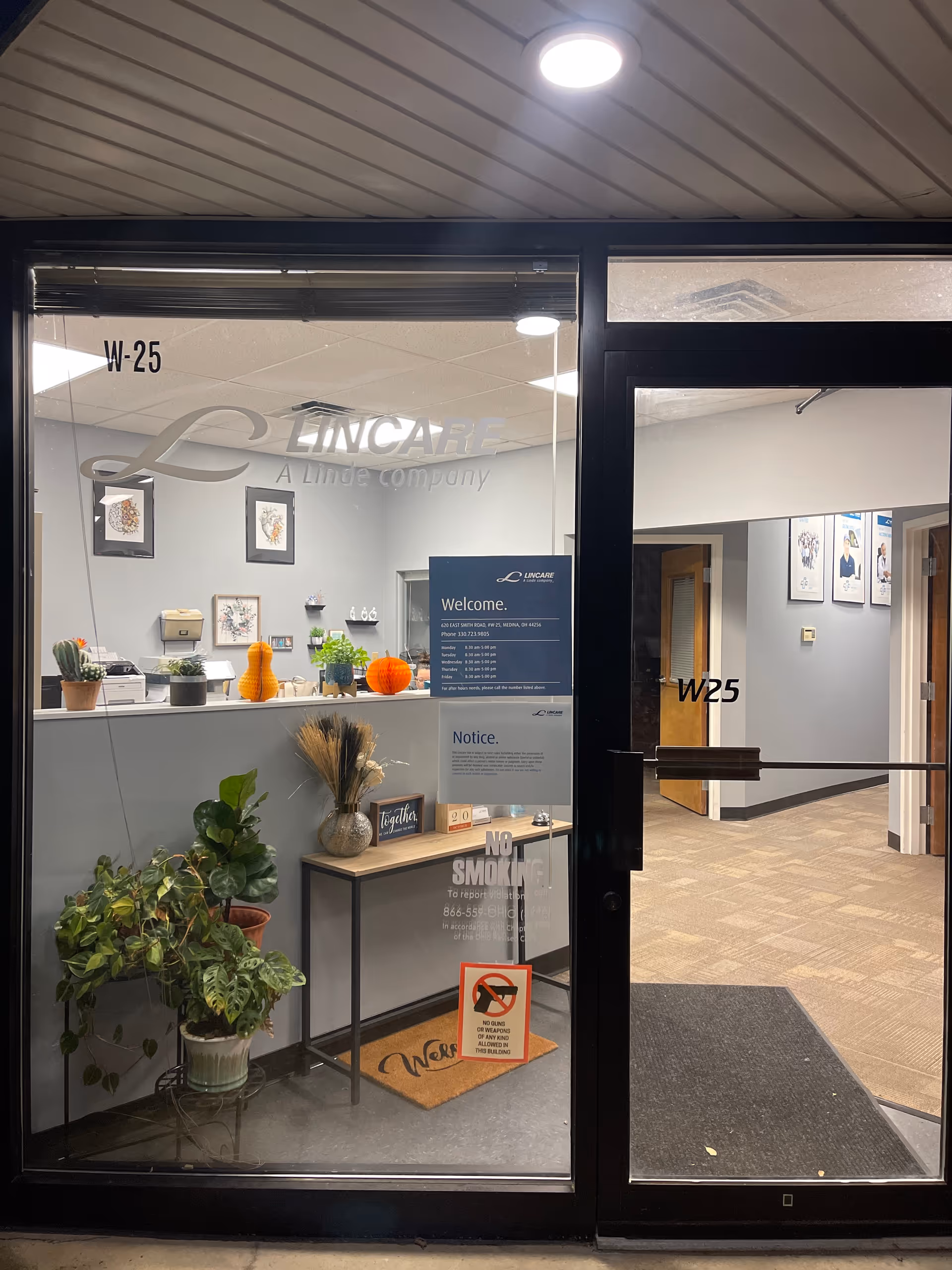 Entrance lobby of LINCARE facility with reception desk, plants, and autumn decor.