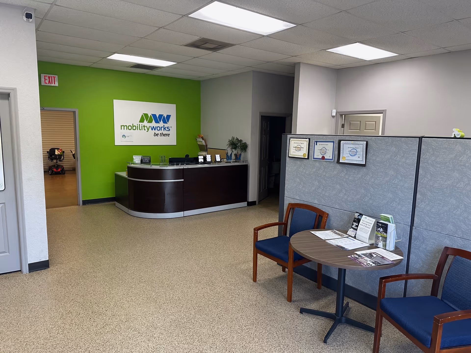 Reception desk against a bright green wall with MobilityWorks sign in a clean lobby.