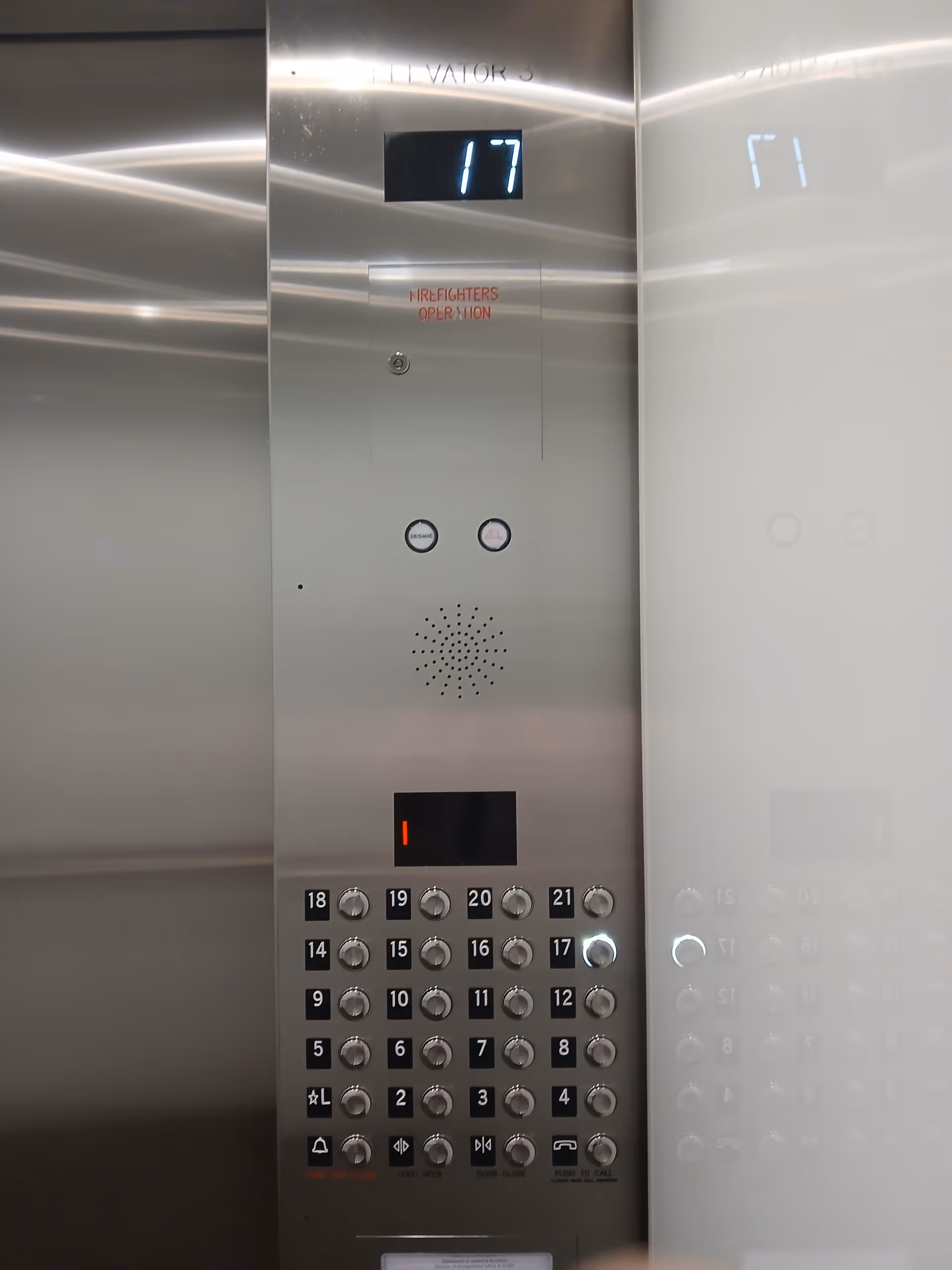 Inside a stainless steel elevator panel with keypad, display, and speaker.