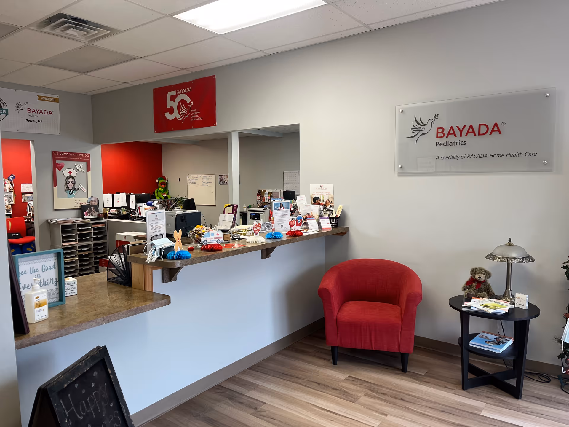 Interior reception area of BAYADA Pediatrics with counter and red chair.