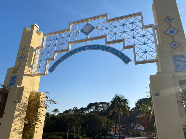 Ornate outdoor entrance arch with lattice design against a clear blue sky.