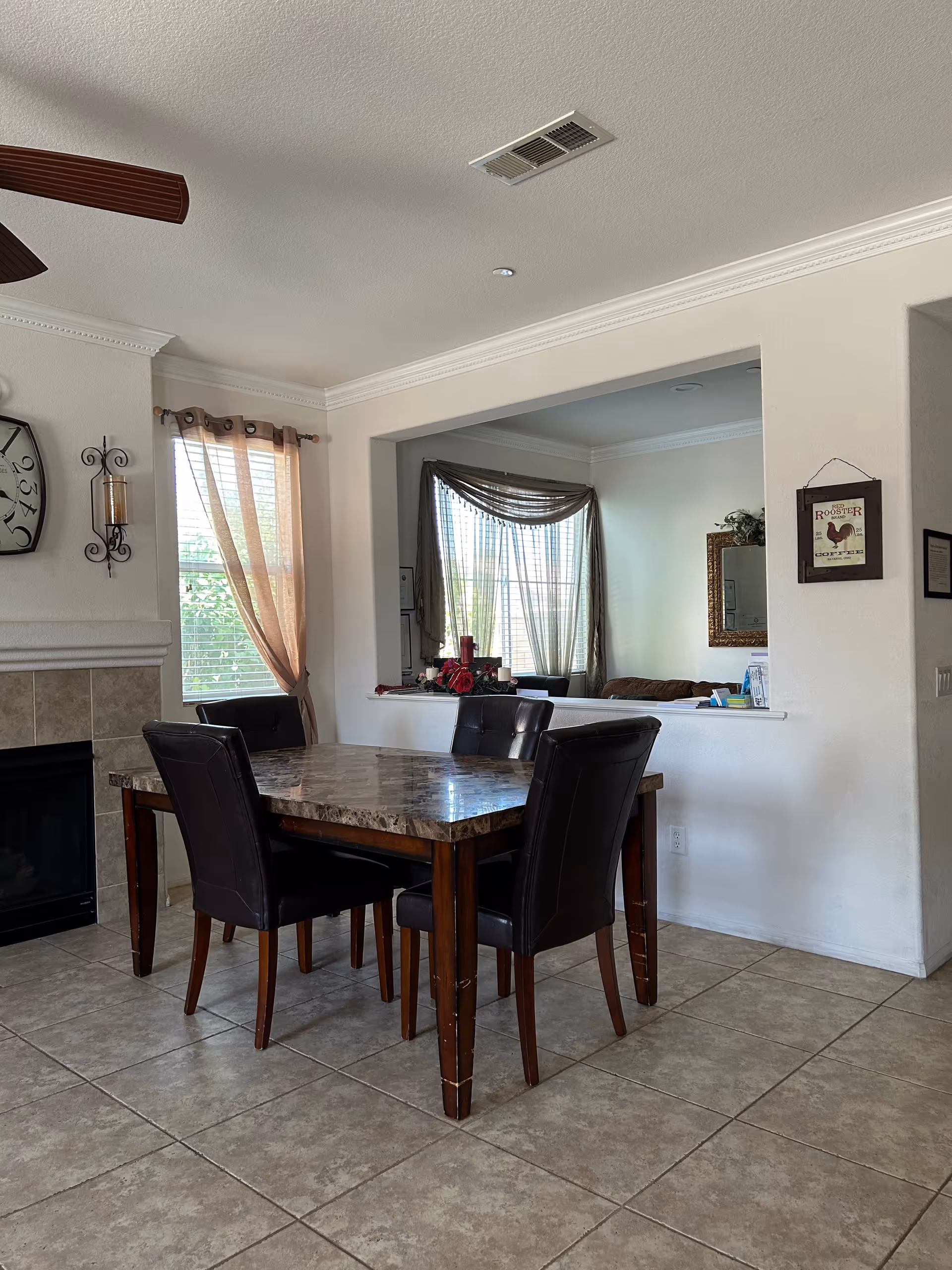 Light-filled dining room with a marble-top table and six dark leather chairs.