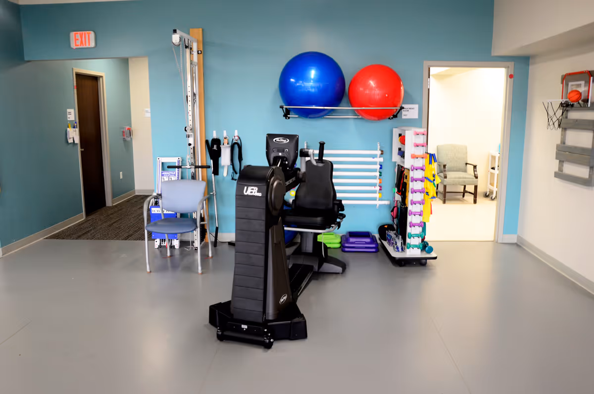 Interior gym area with exercise equipment, weights, and stability balls.