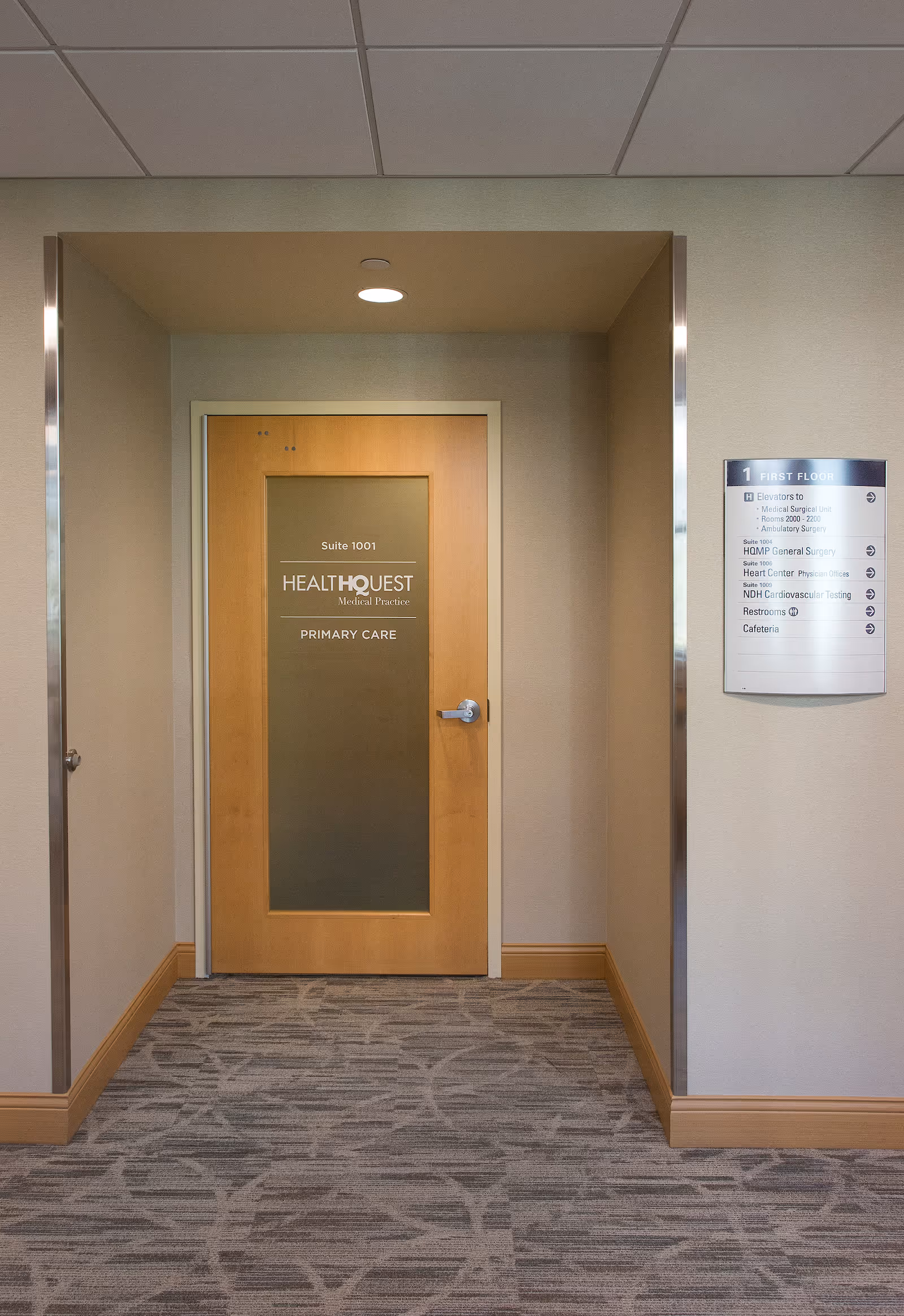 Interior hallway leading to Suite 1001 HealthQuest Primary Care with a nearby directory sign.